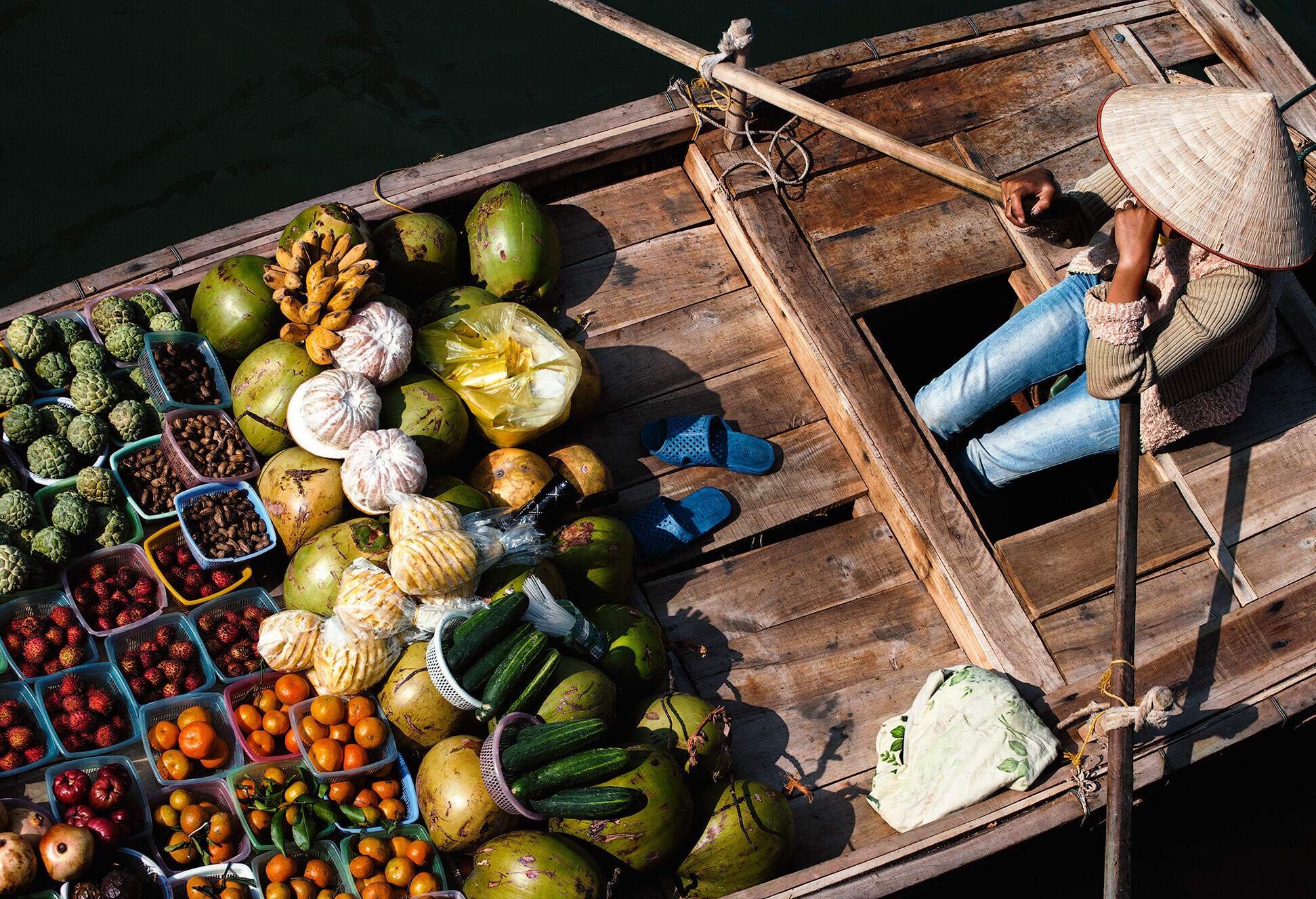A lady fruit vendor sits on her wooden boat.