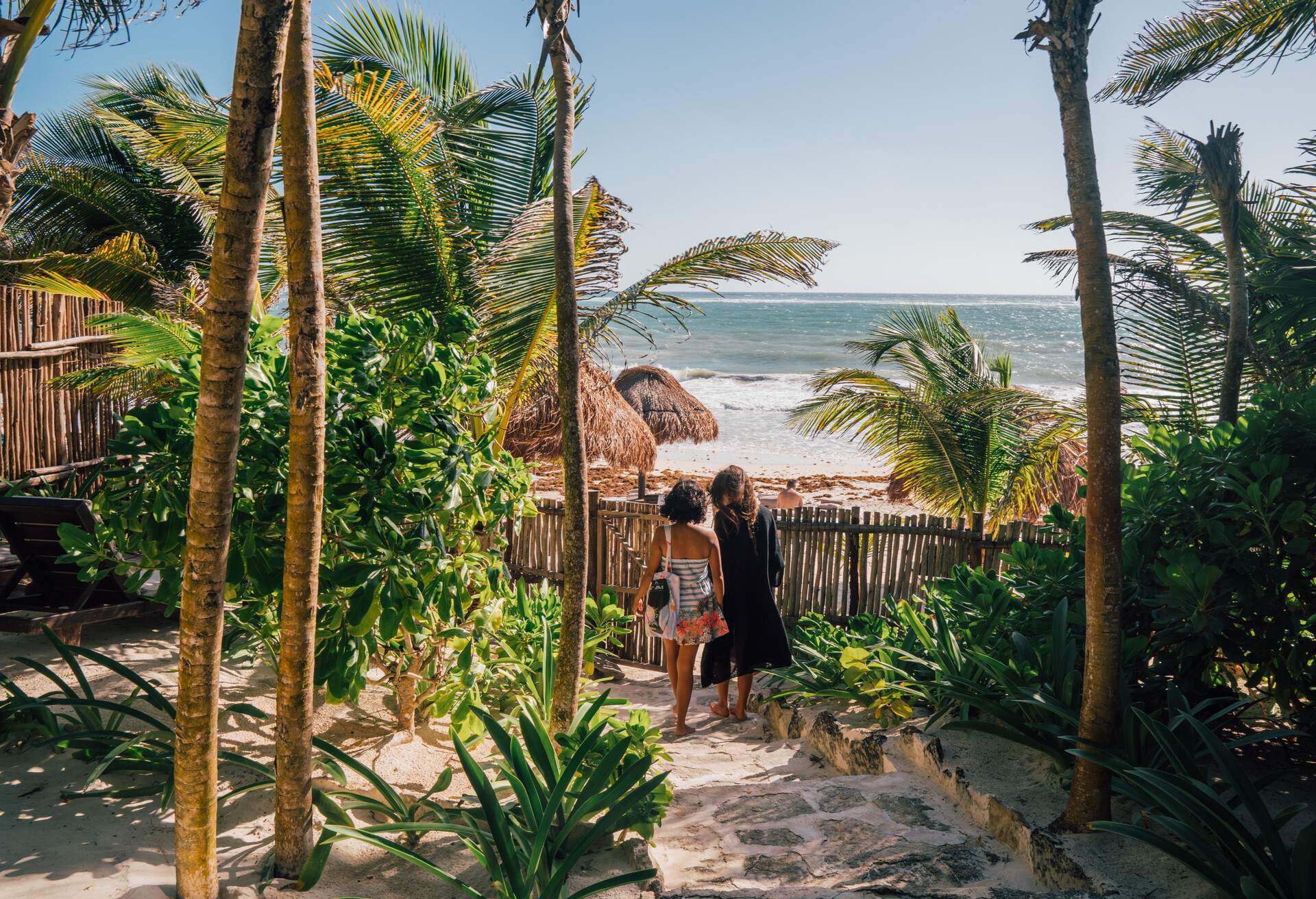 Mexican friends take a trip to Tulum and stay in a resort Boutique Hotel on the Beach. Friends walking on pathway of Boutique Hotel gardens. 