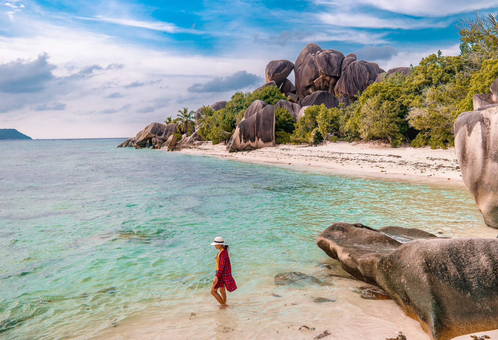 Tropical island with white beach and clear ocean of La Digue Seychelles, Young woman at the beach with giant rocks of the Seychelles
