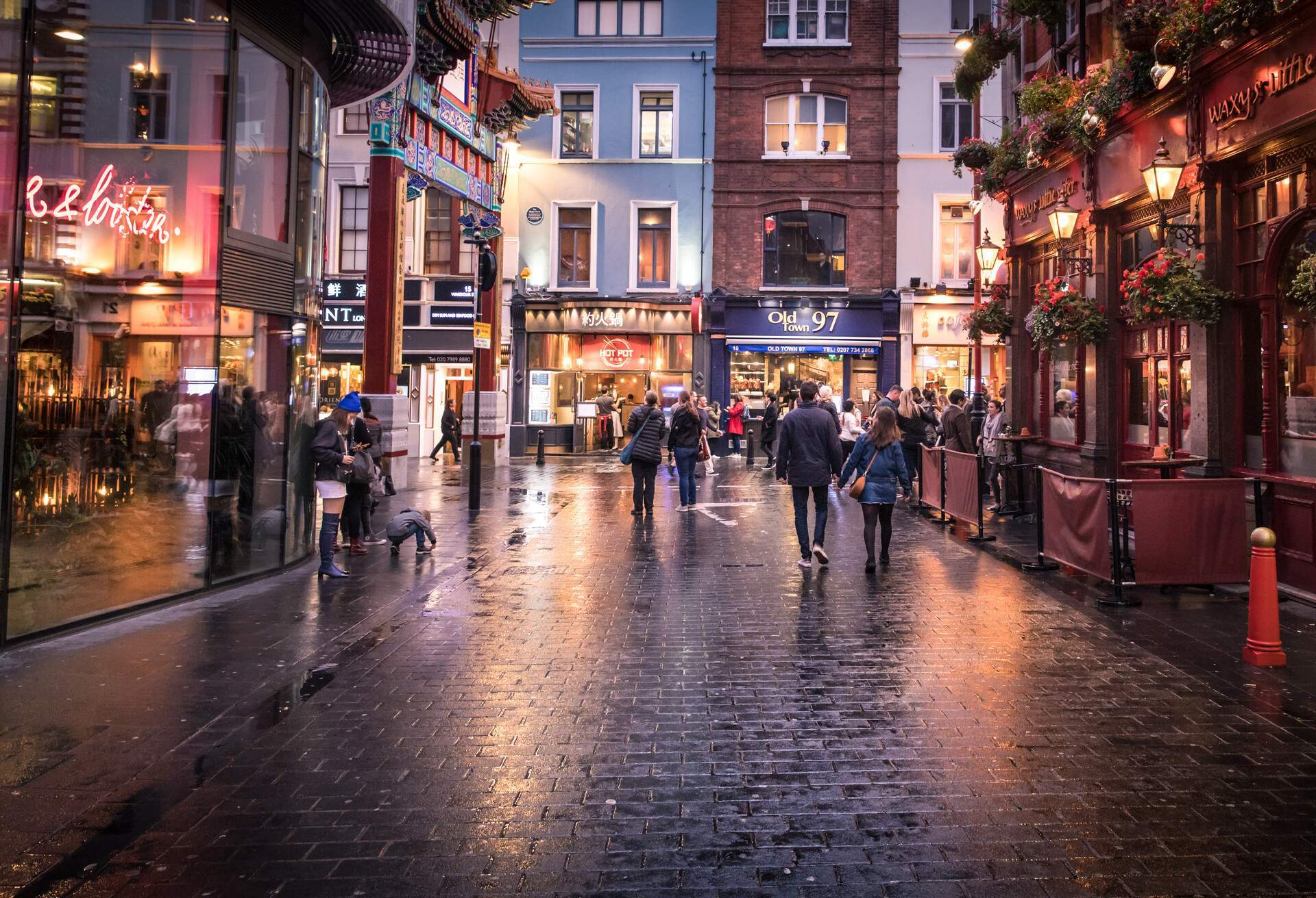 a street in London's Soho district in the evening as the lights come on