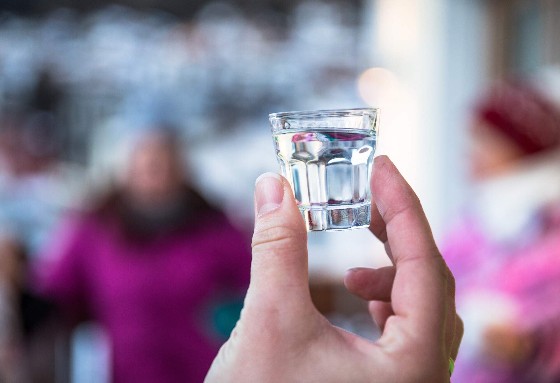 Hand holding a filled shot glass.