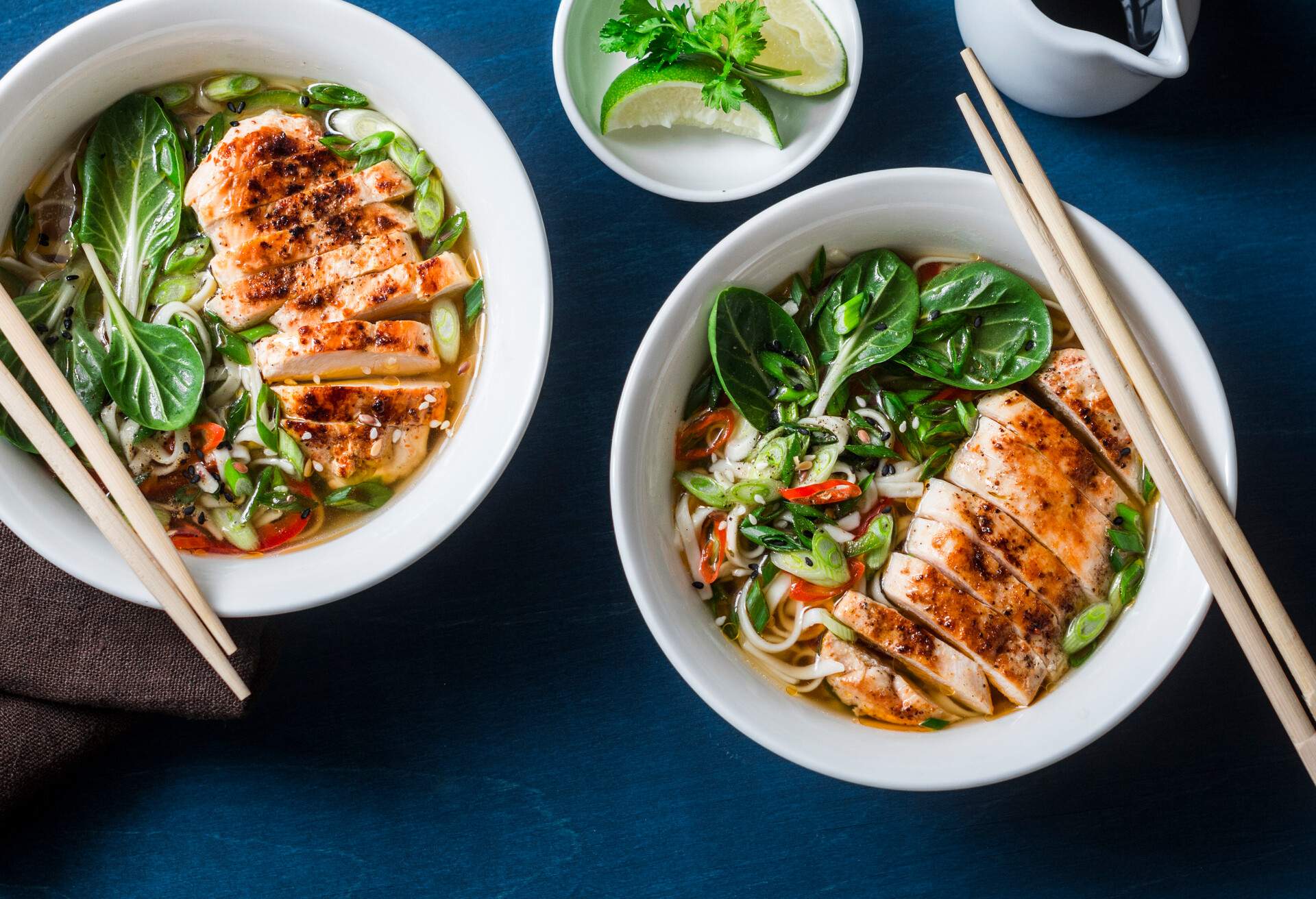 Chicken, noodles and vegetables asian style soup on a blue background, top view