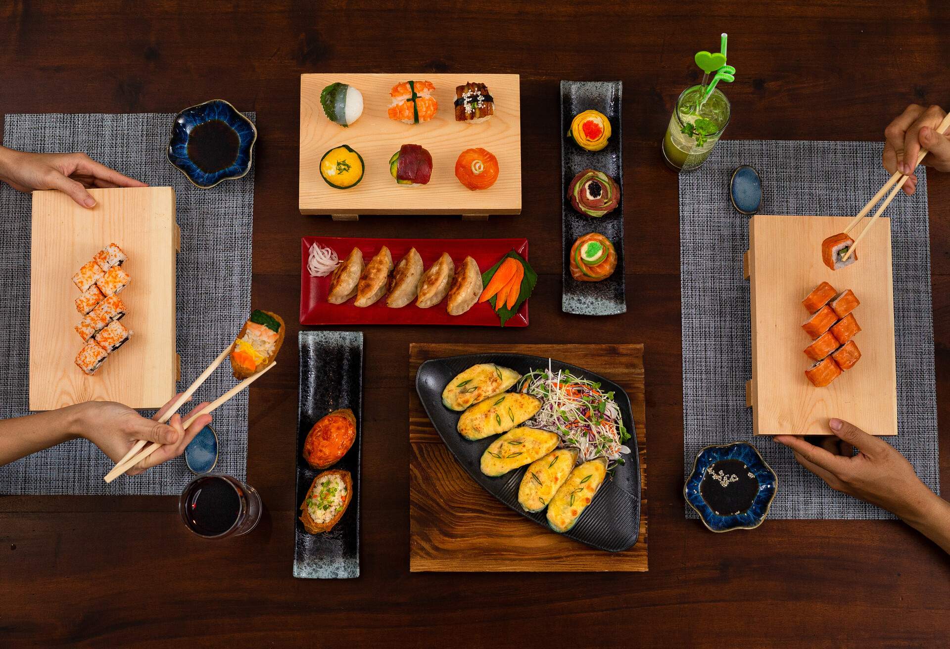 Top view of Japanese various side dishes: Philadelphia, Tuna uramaki, Flower sushi set, Gyoza, baked mussels, tuna uramaki, onigiri and inari sushi set