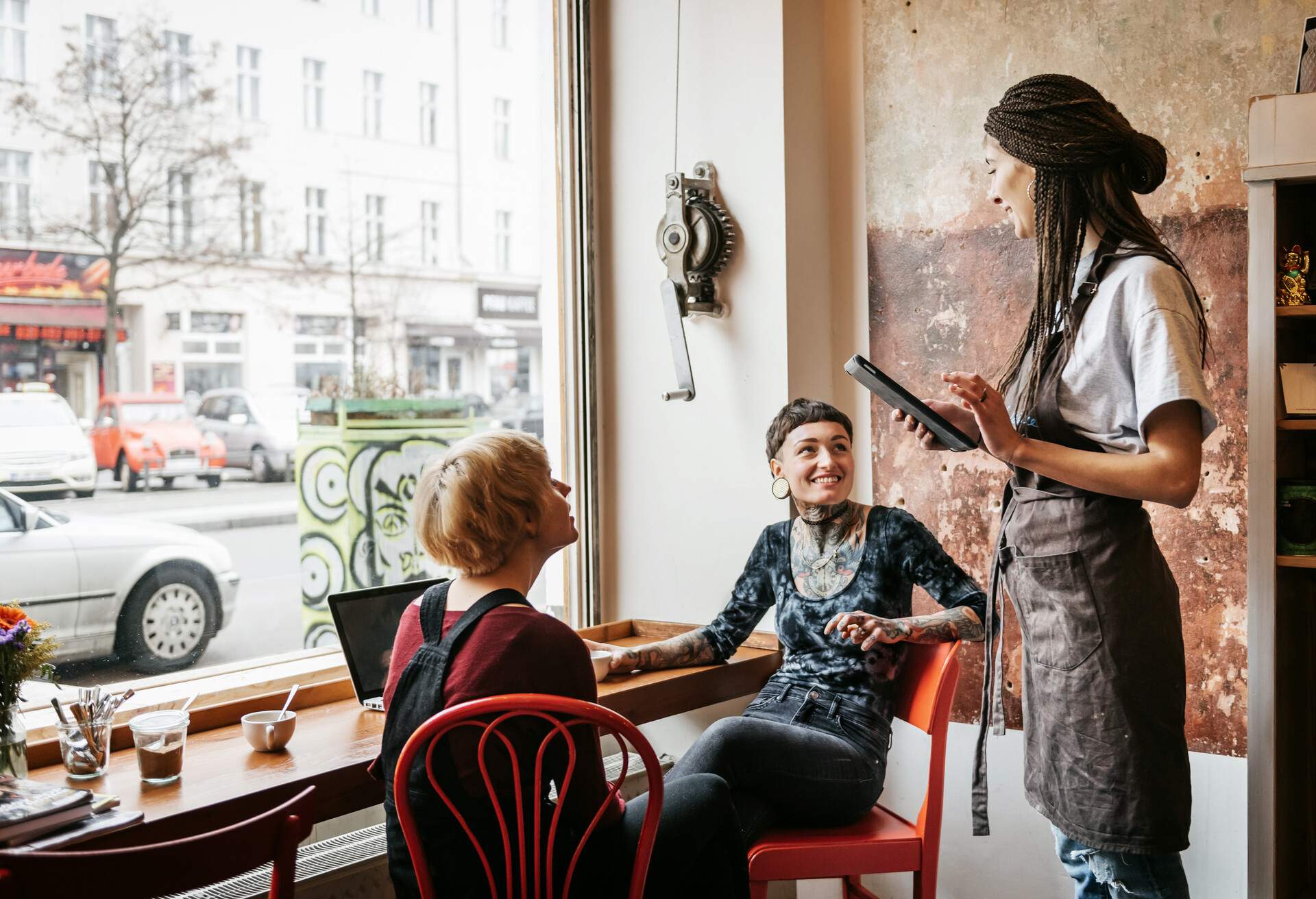 A waitress in a café taking orders of two customers sitting at the bar counter.