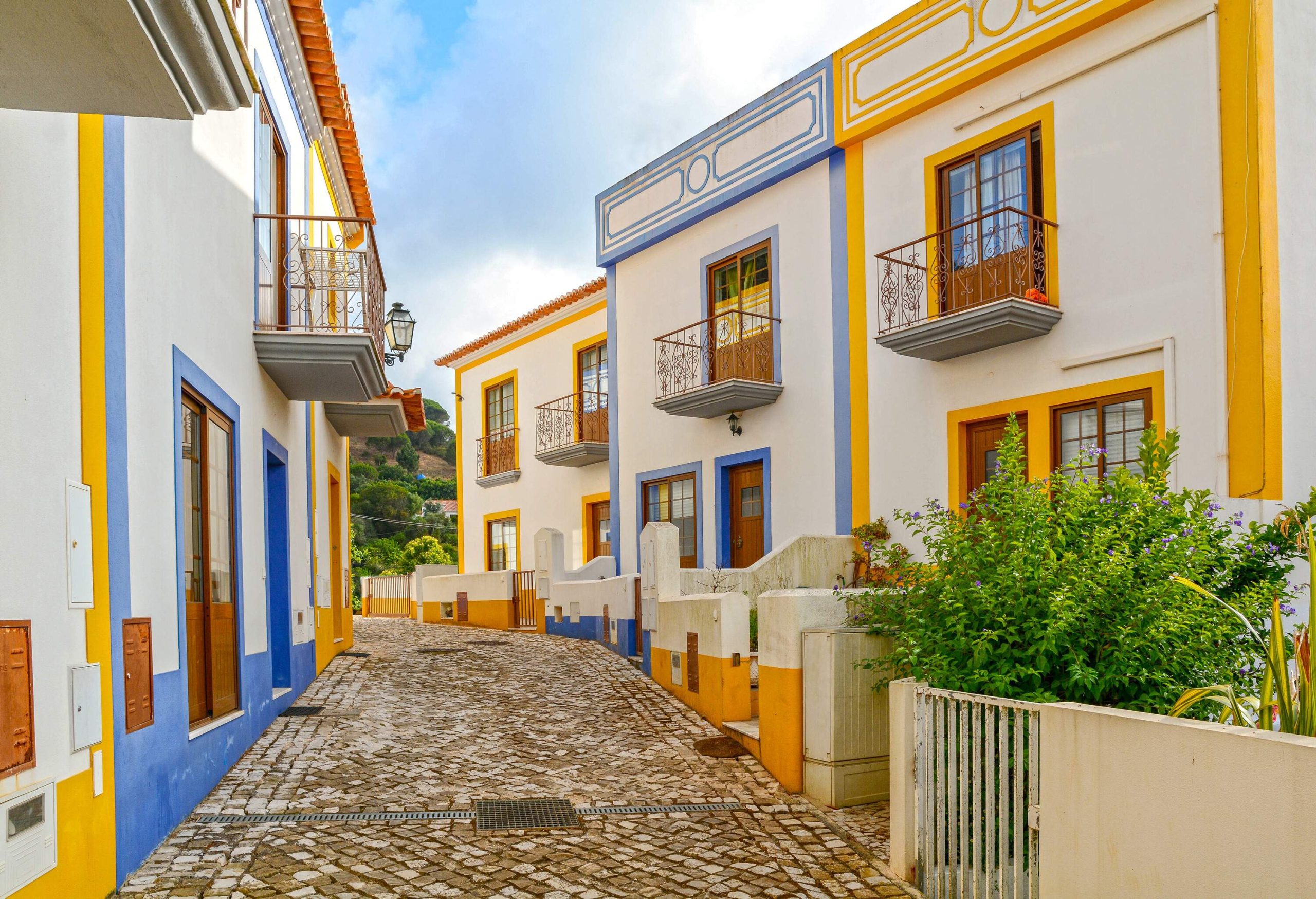 Cobblestone streets lined with colourful, identical houses painted white with alternating blue and yellow borders.