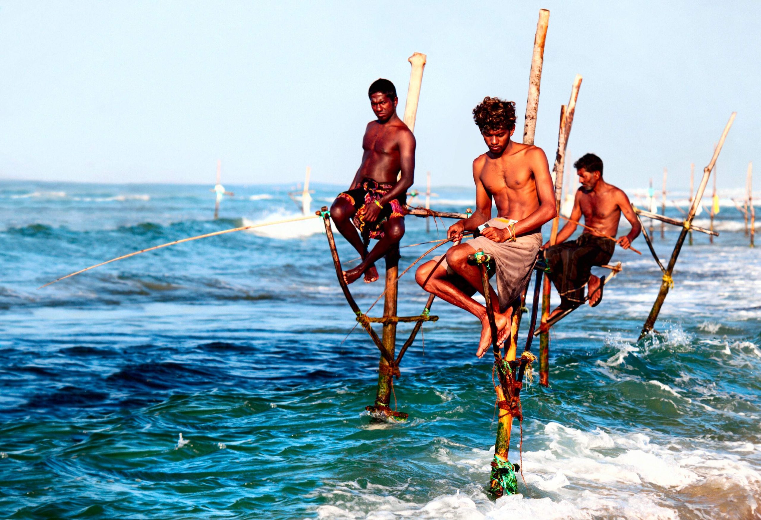 Fishermen perched on stilts, patiently fishing above the water's surface.