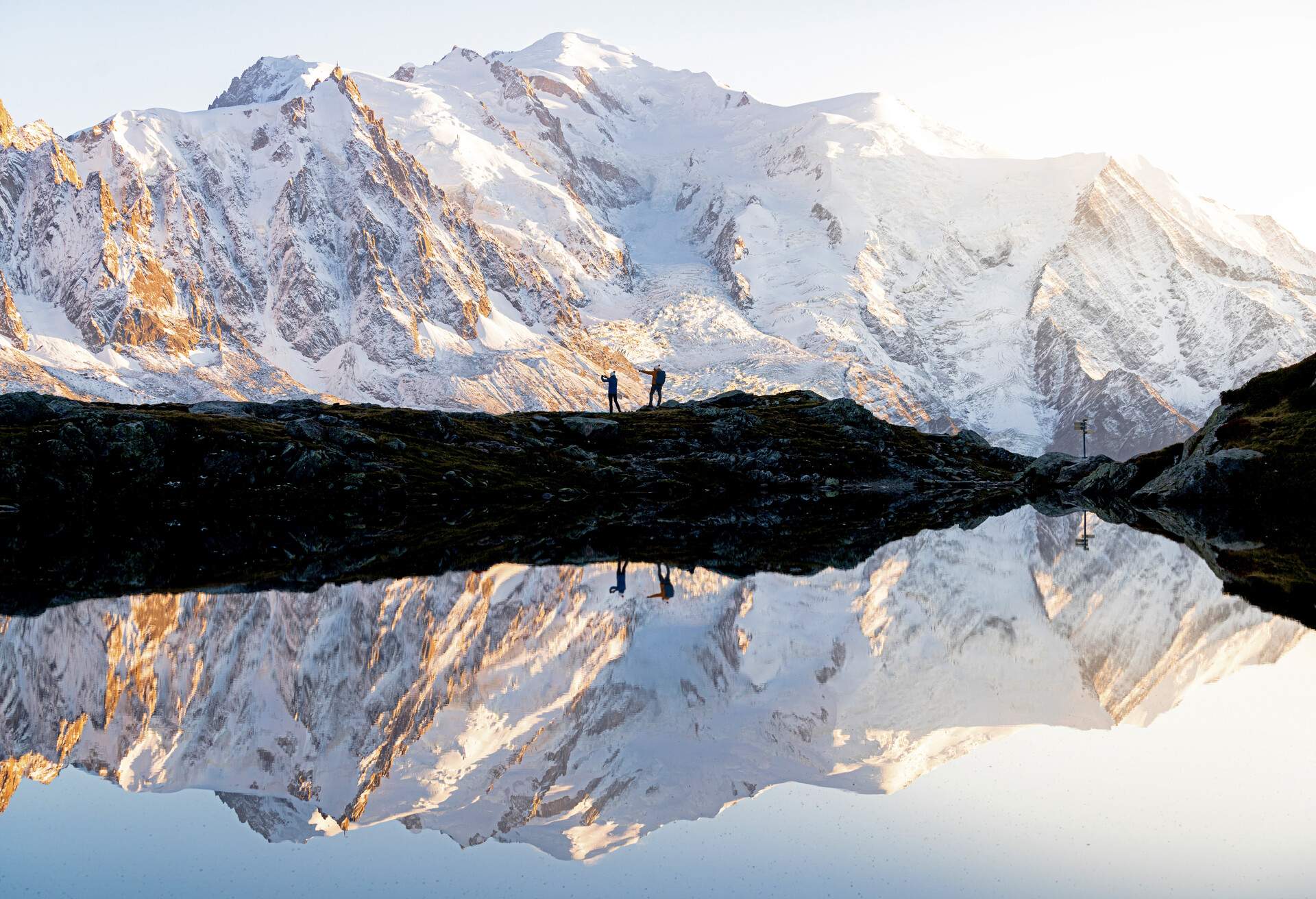 Silhouettes of people admiring sunset over Mont Blanc covered with snow mirrored in Lacs des Cheserys, Haute Savoie, France 