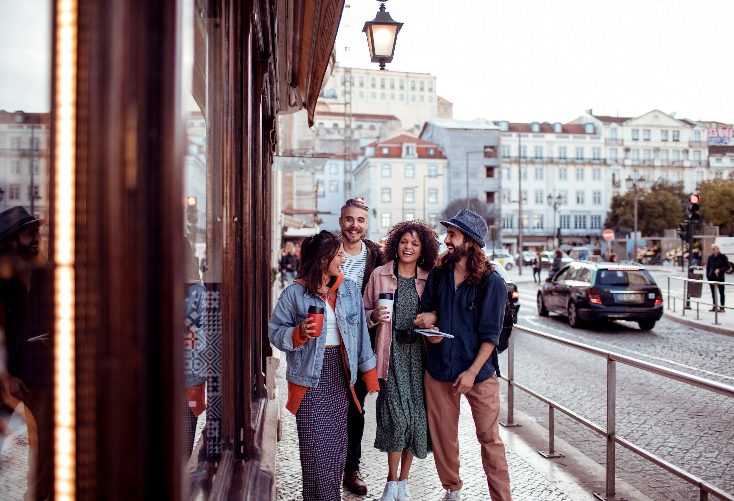 A group of friends laughing as they walk on a city sidewalk.