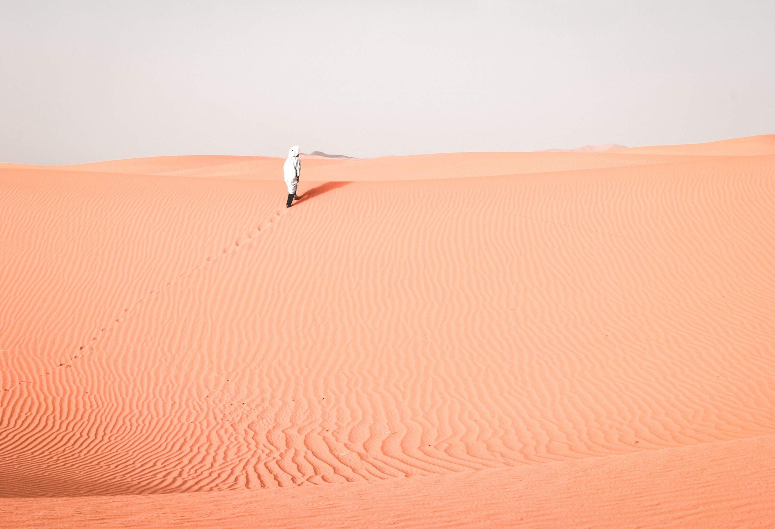 An individual in a traditional white dress on a desert.