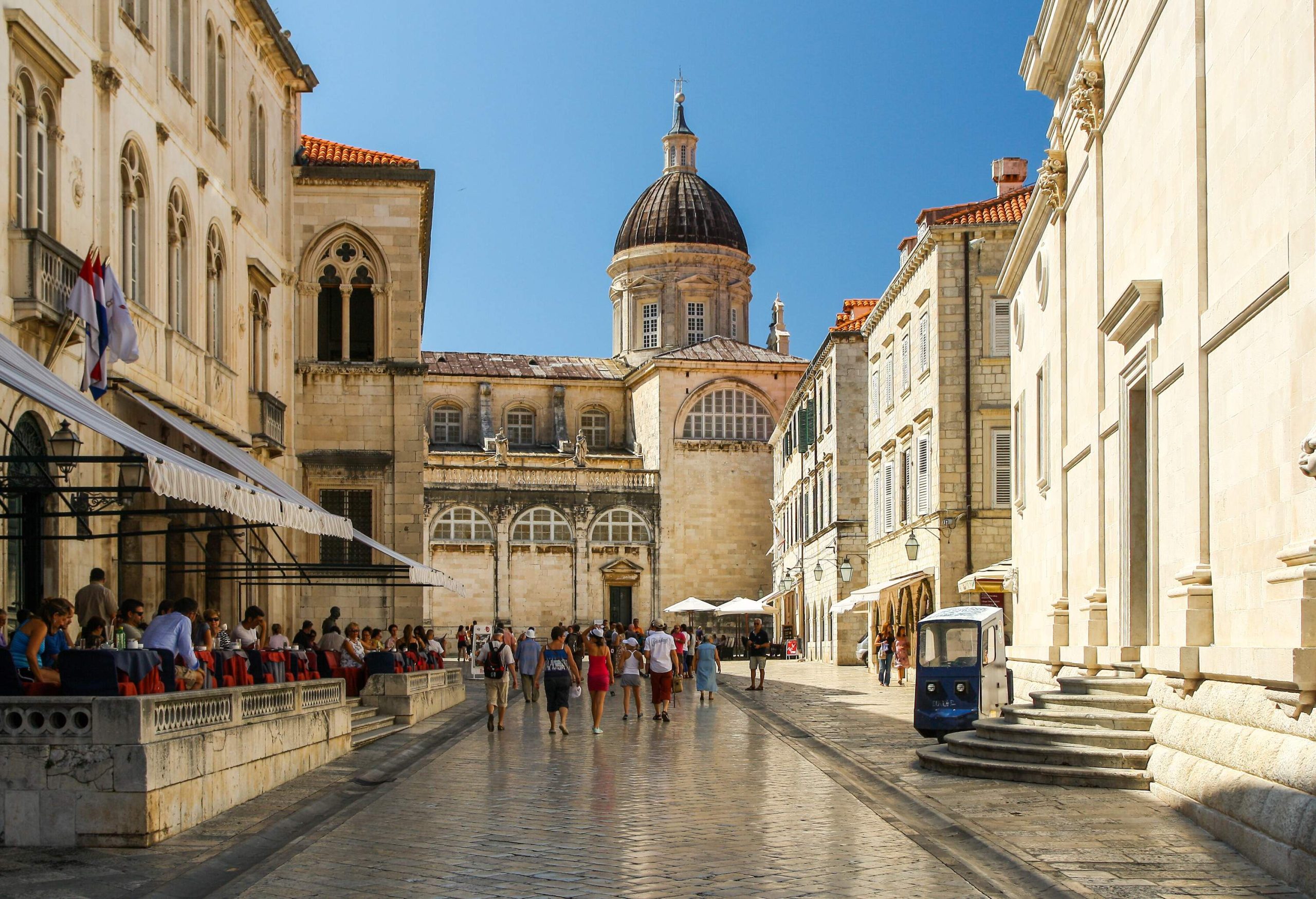A cobbled street lined with classic buildings, outdoor restaurants and a Baroque architecture cathedral in the centre.