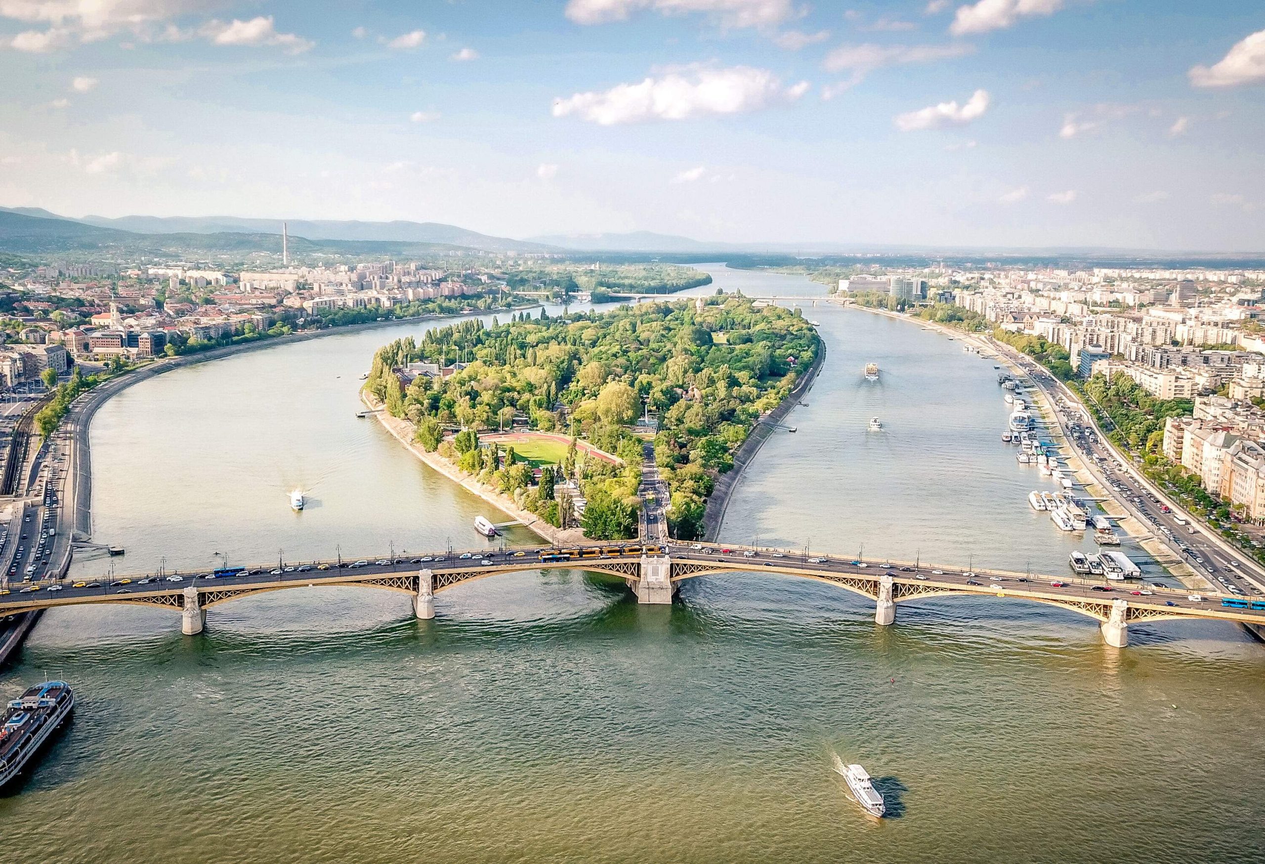 A wooded island in the middle of a river crossed by a long bridge.