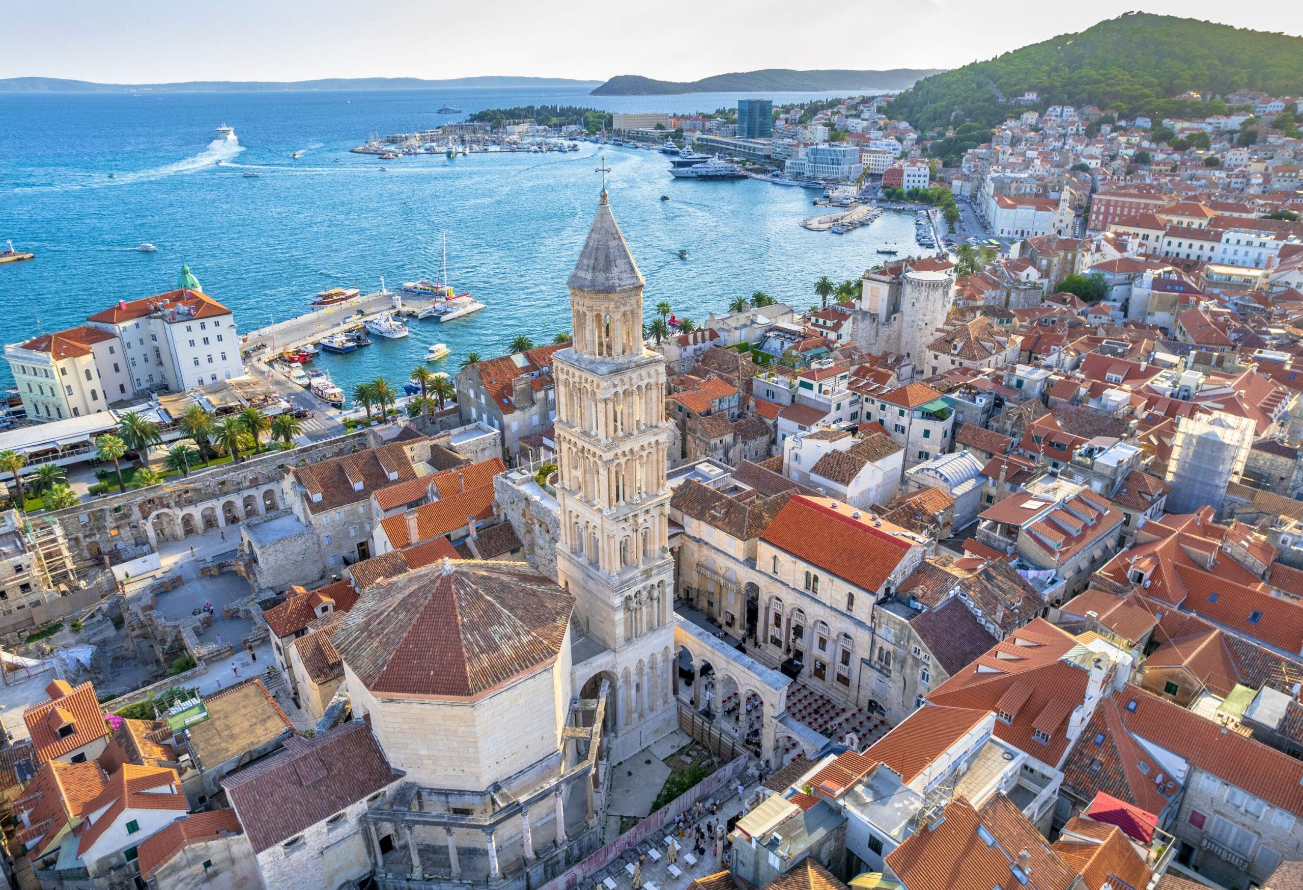 A palace's Romanesque bell tower soars above a coastal city's urban landscape.