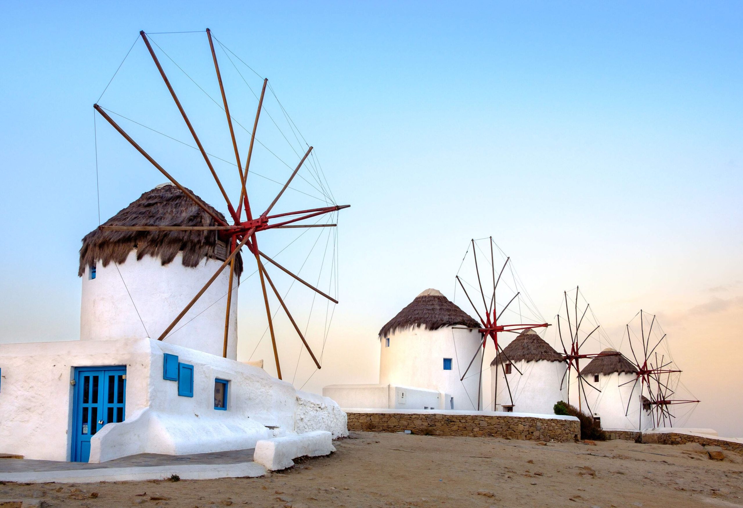 A row of iconic white round windmills on a hill at dusk.