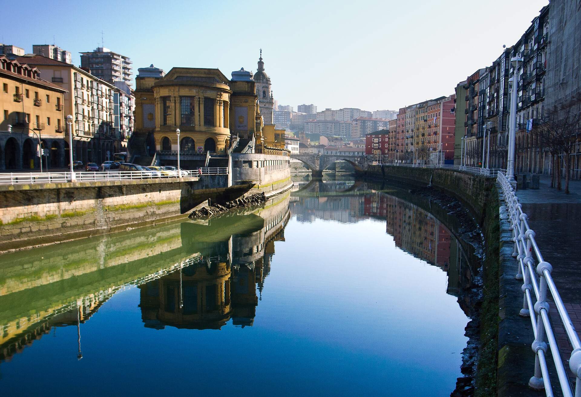 Colourful buildings lined up on both sides of the river with calm water crossing the bridge.