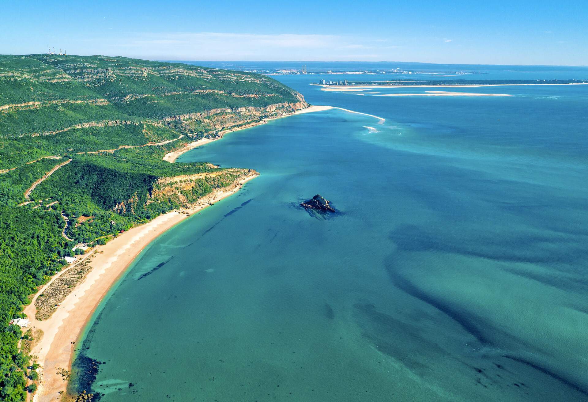 Aerial view of a lush island surrounded by the tranquil blue sea.