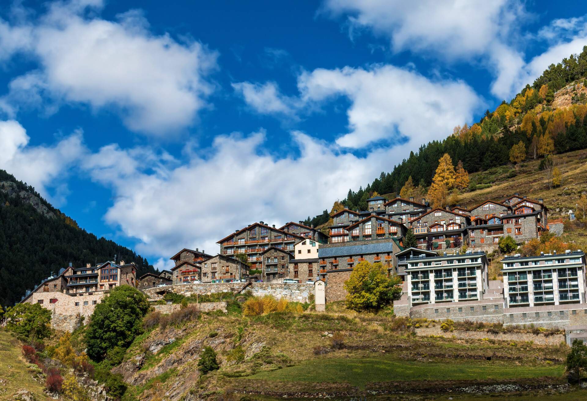 A town with multi-storey buildings that is situated on a hillside and is encircled by luxuriant flora.