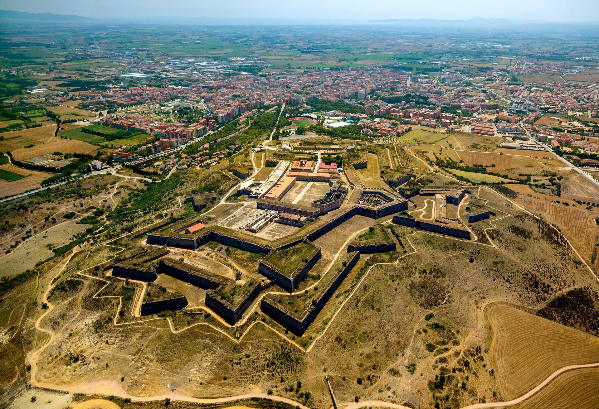 A large military fortress with bastions situated atop a hill with views of the entire city.
