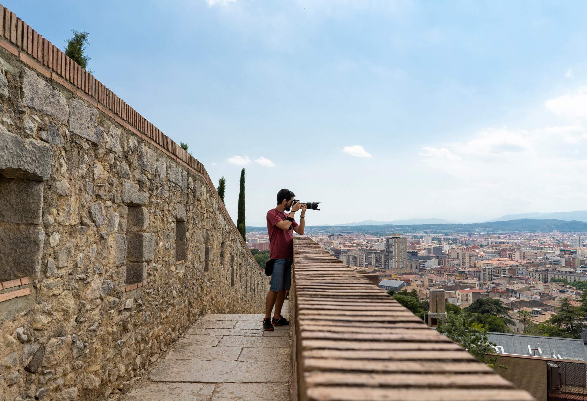 A man in an elevated area taking a picture of the populated urban area.