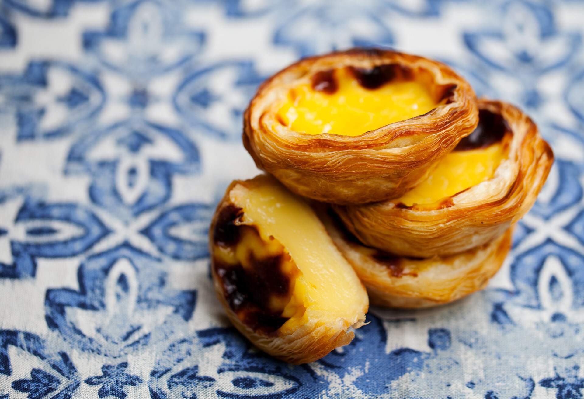 A stack of egg tarts dessert on a blue background.