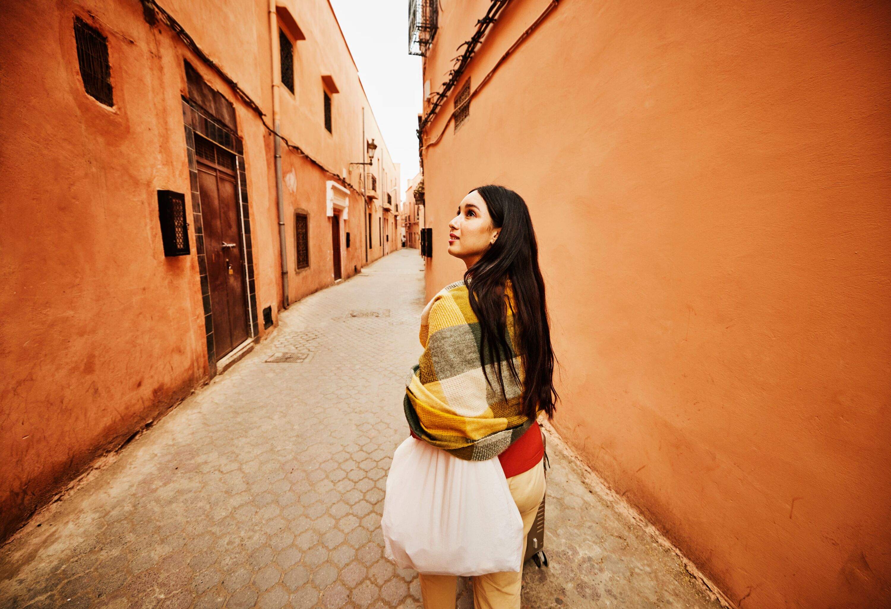 Wide shot of female solo traveler exploring the streets of the Medina of Marrakech while on vacation