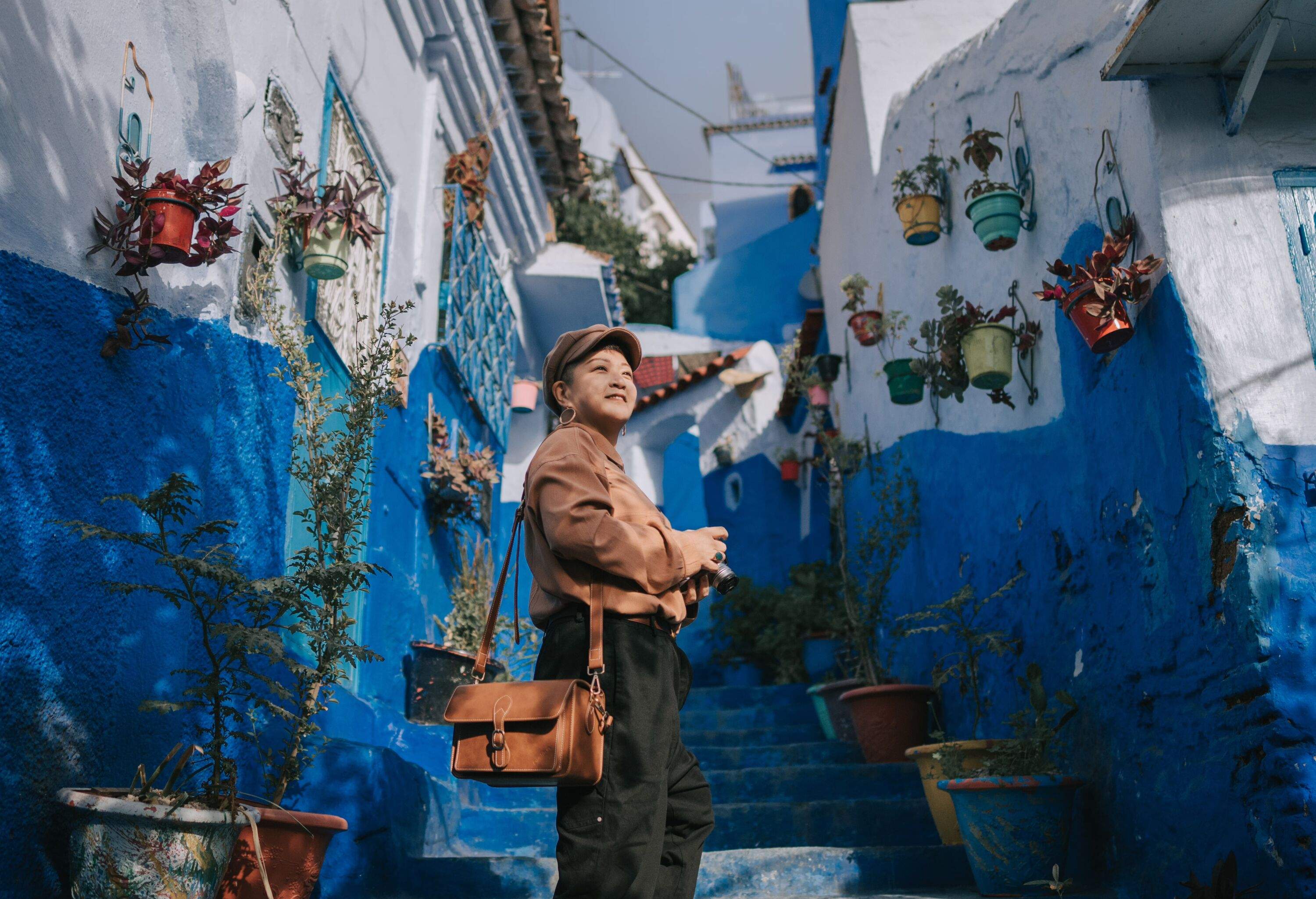 Asian Chinese female tourist standing at alley in Chefchaouen, Morocco in the morning smiling