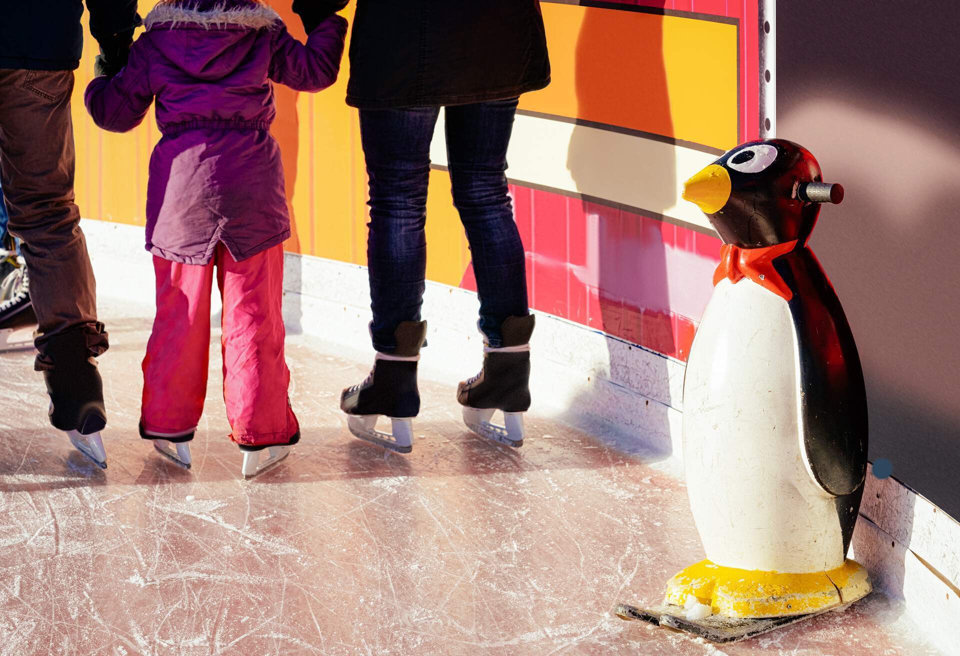  Des familles patinent sur la patinoire du marché de Noël à Berlin, aidées par des supports en forme de pingouin et des assistants