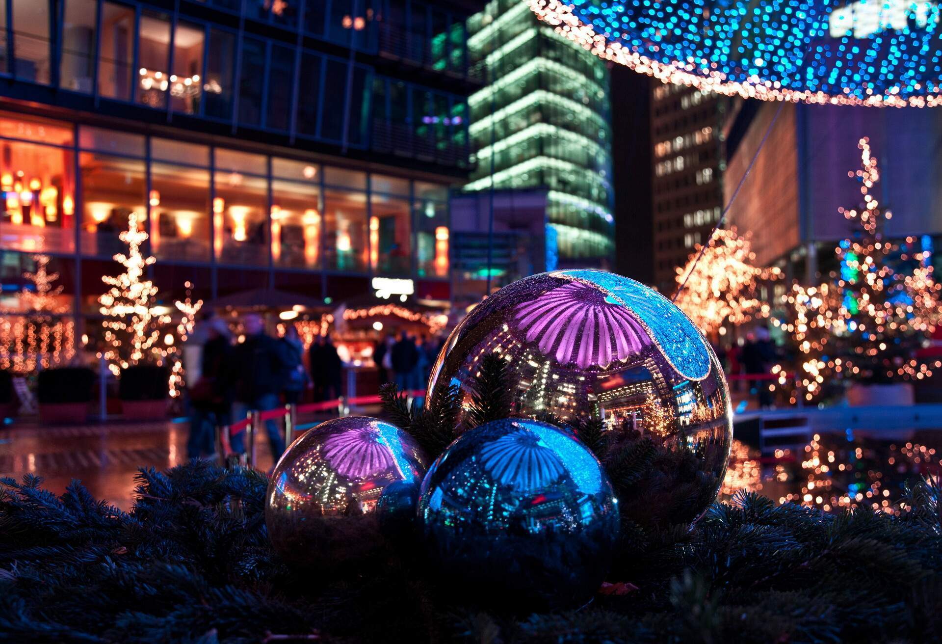 La splendide nuit du marché de Noël, illuminée dans le Sony Center de Berlin, où l'on aperçoit le marché qui se reflète dans les boules métallisées.