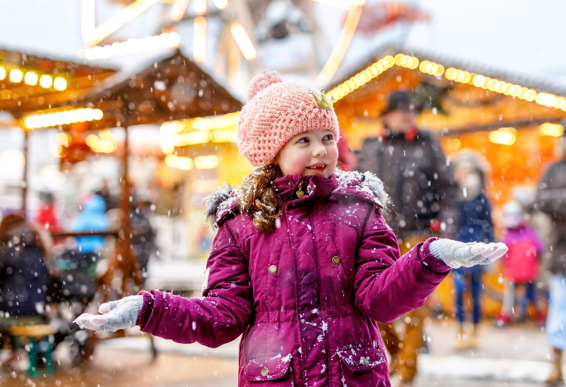 Petite fille mignonne s'amusant sur un marché de Noël traditionnel allemand pendant une forte chute de neige. Enfant heureux profitant du marché familial traditionnel en Allemagne, à Francfort. Petite fille riant en vêtements colorés.