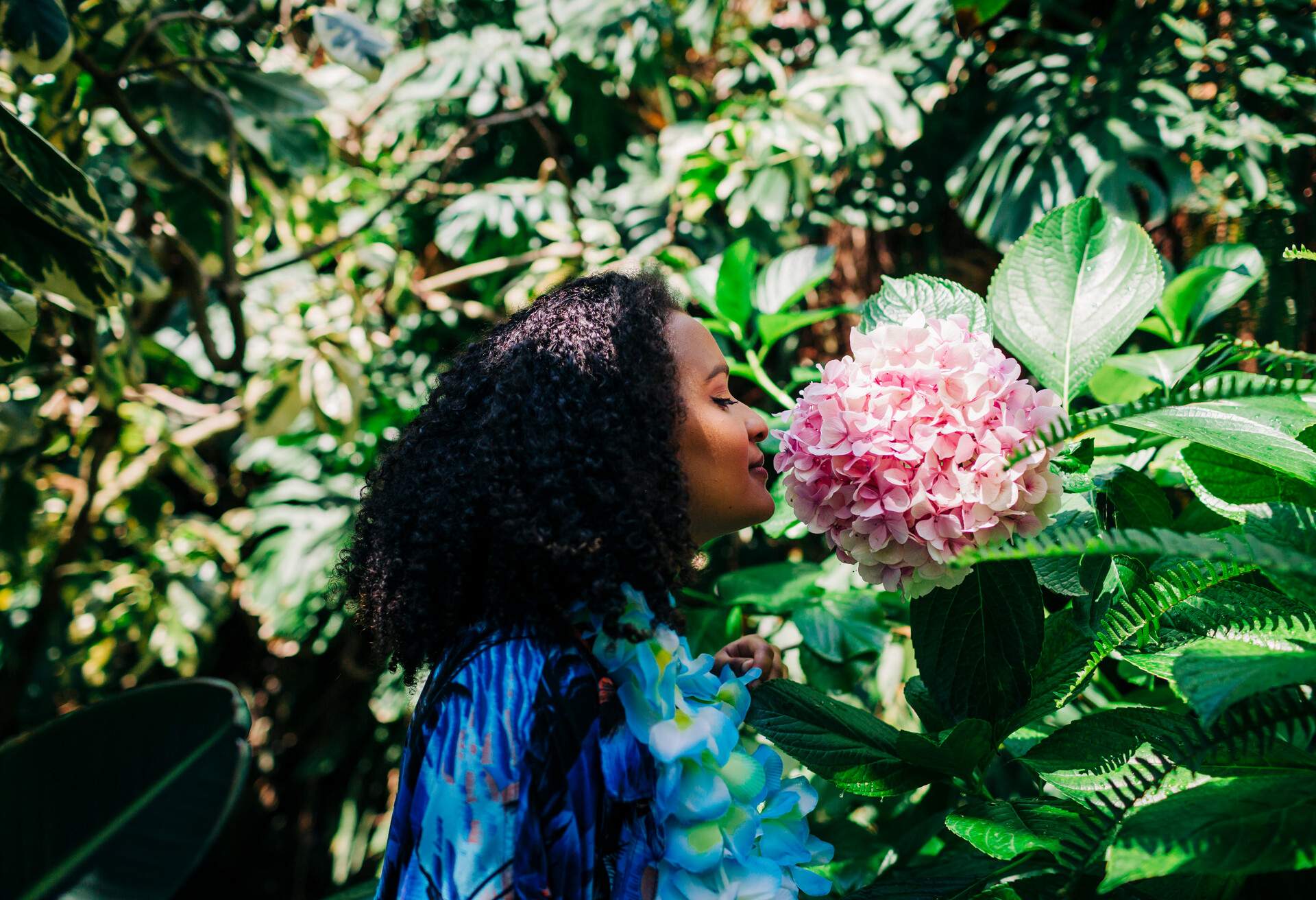 A woman savouring the scent of a large bunch of pink flowers.