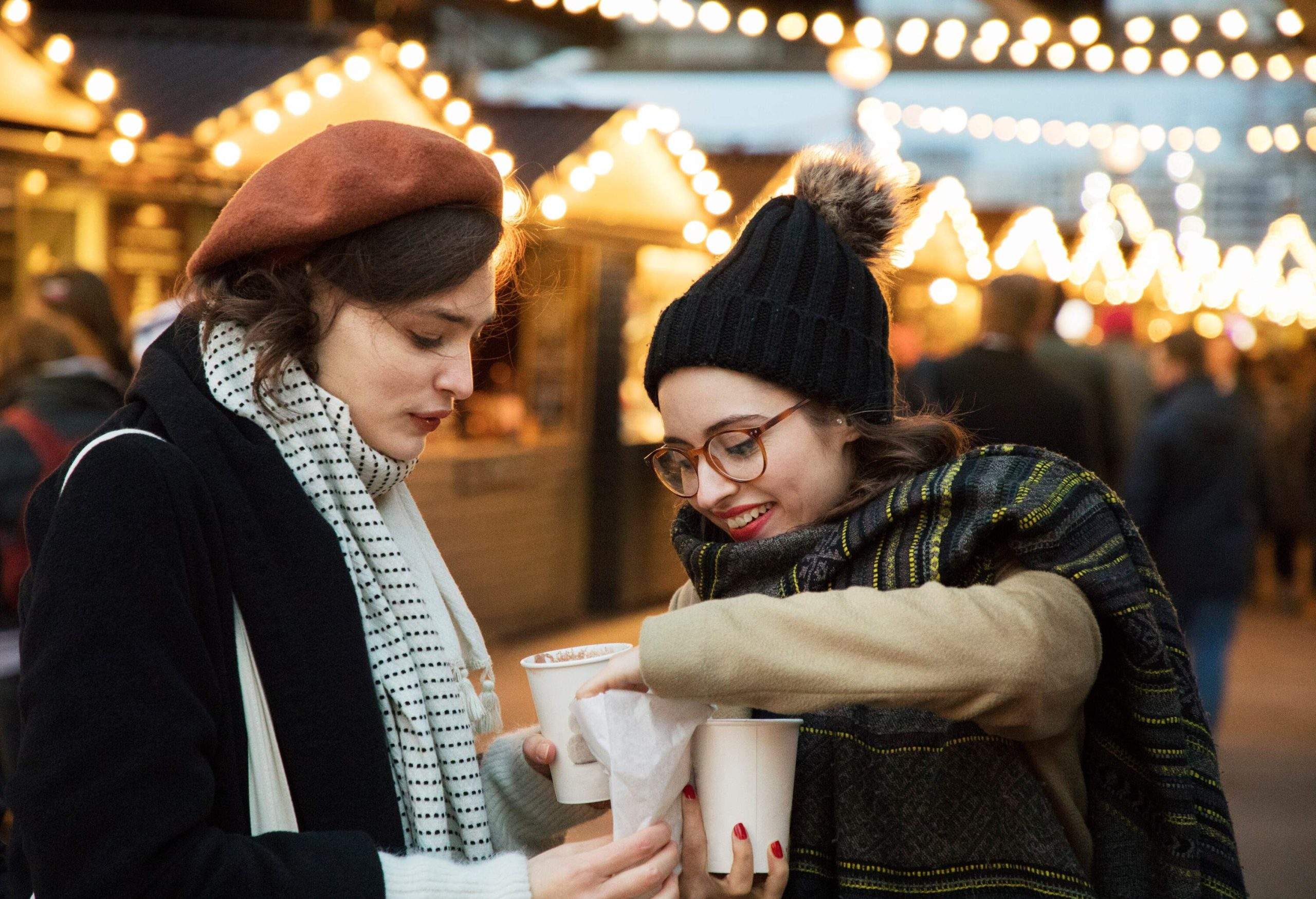 Deux amies partageant nourriture et boissons au marché de Noël