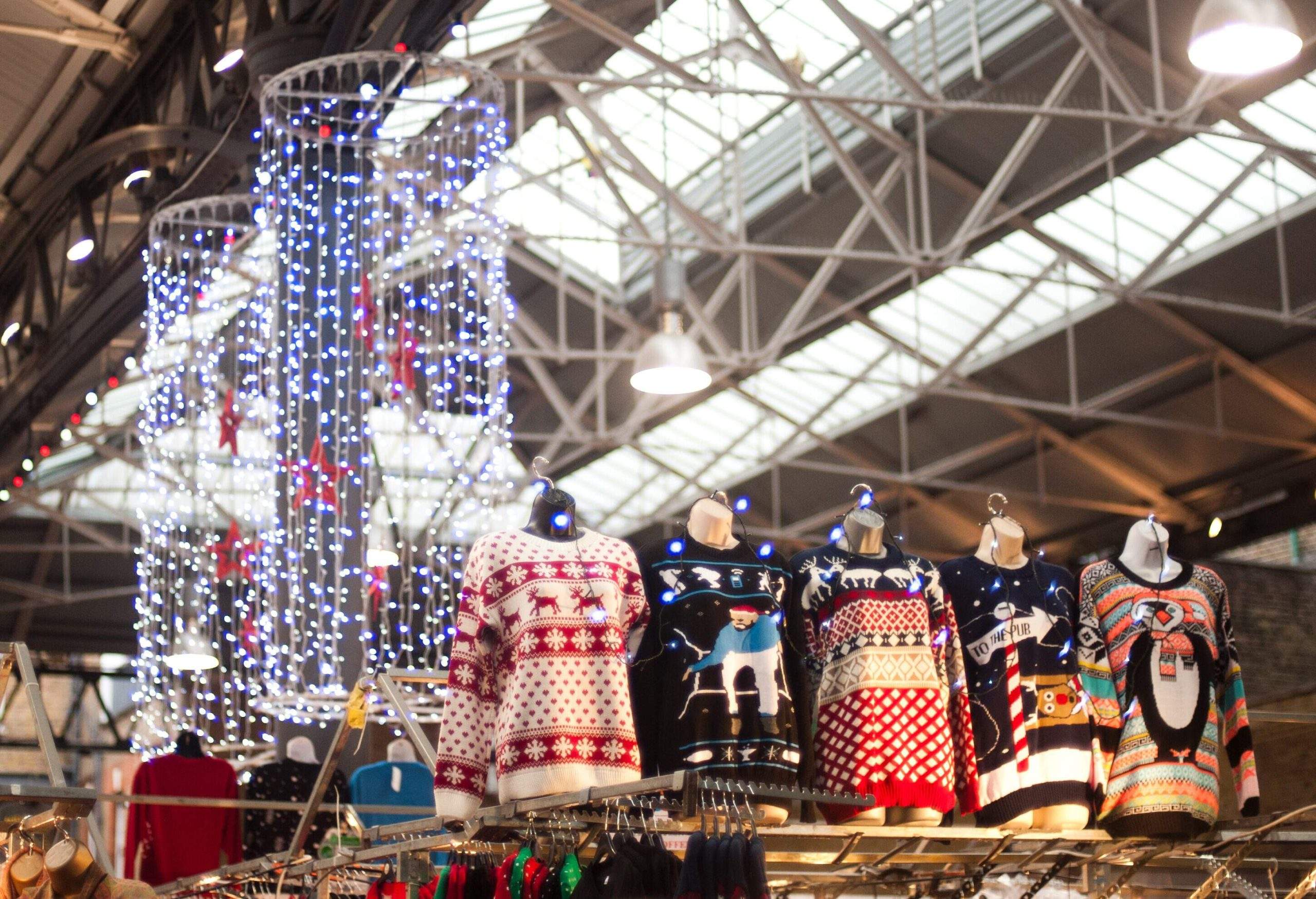 Un marché de Noël avec de nombreuses lumières féériques, y compris une sélection de pulls de Noël