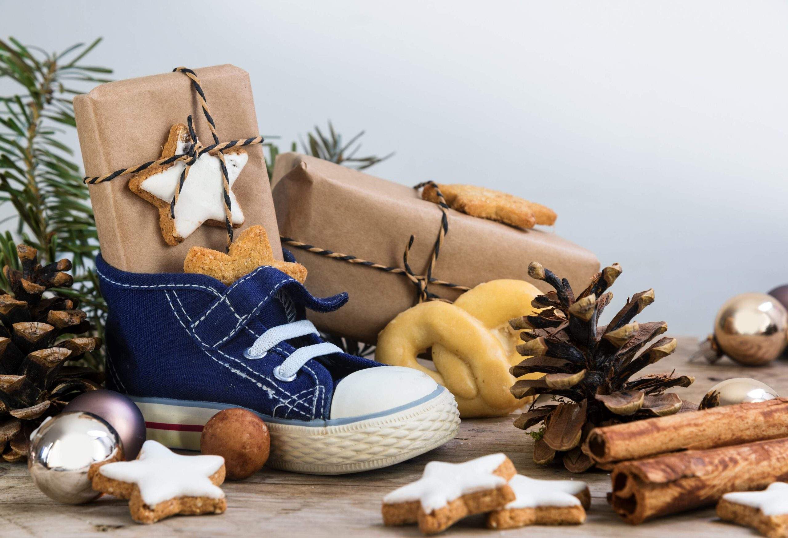 Des chaussures d'enfant, des cadeaux, des biscuits et des décorations de Noël sur du bois.