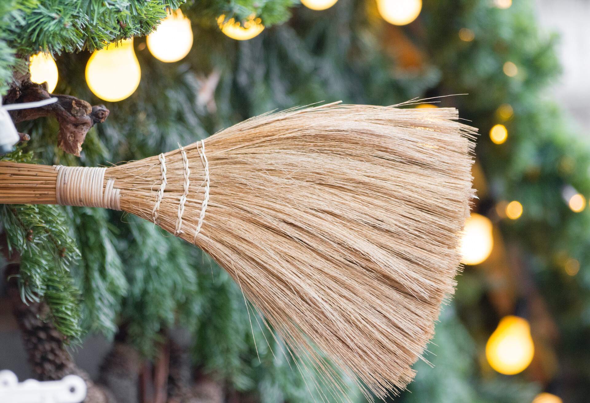 Un balai en bois devant un sapin de Noël illuminé