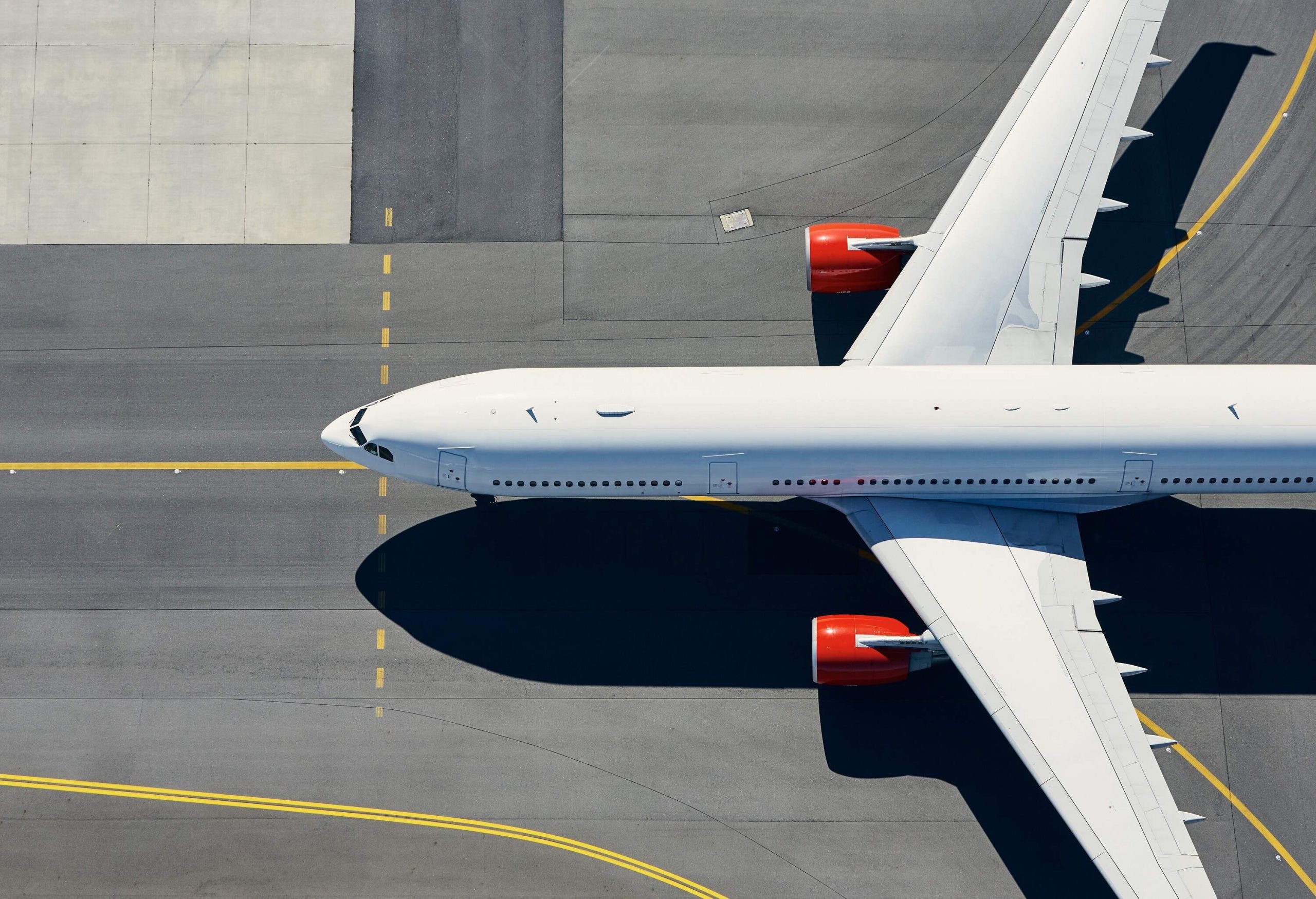 A white airplane traverses a runway with yellow side stripe markers.