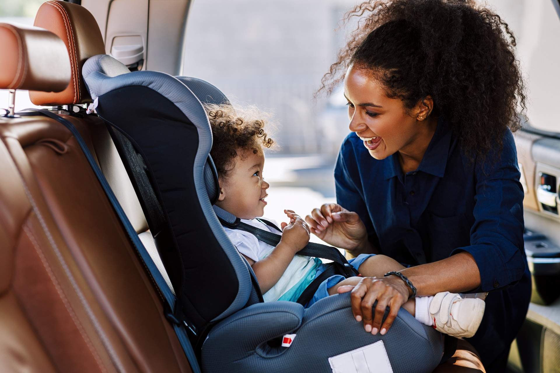 a woman smiling at her child seating in a car seat