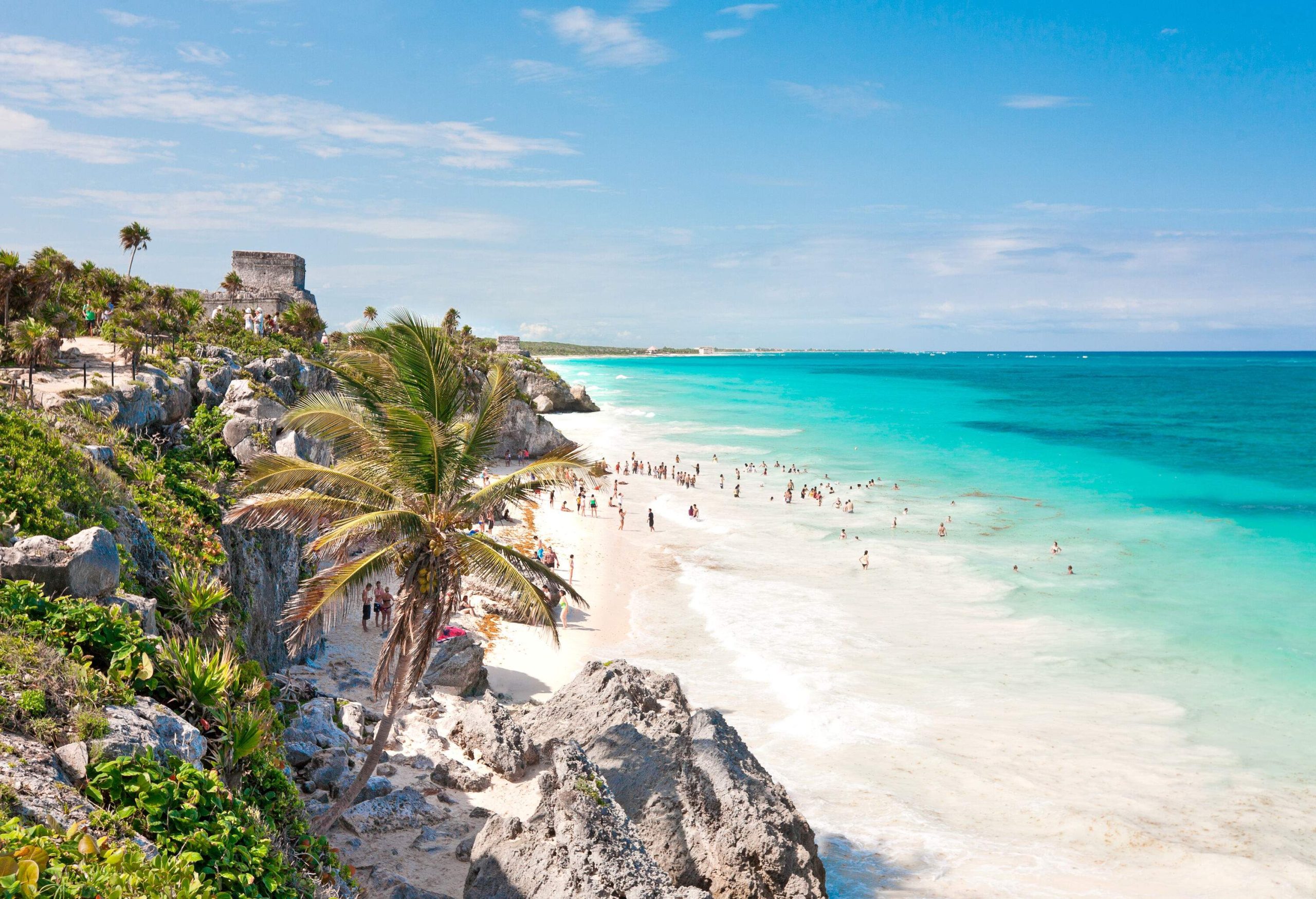 People enjoying themselves in the turquoise-coloured sea with a white sandy beach.