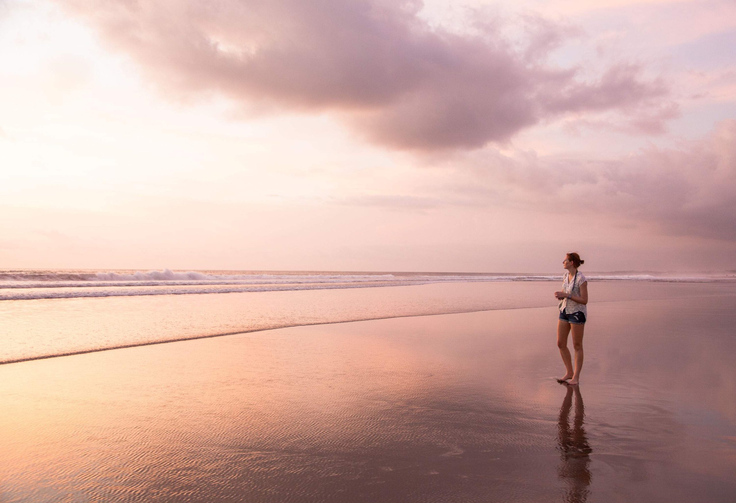 A woman gazing out towards the ocean as she stands on the shore.