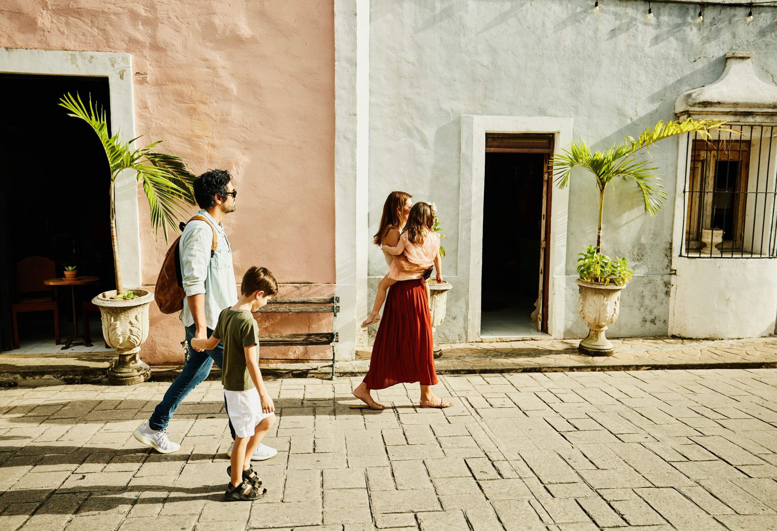 A four-person family strolls by a door on a residential street.