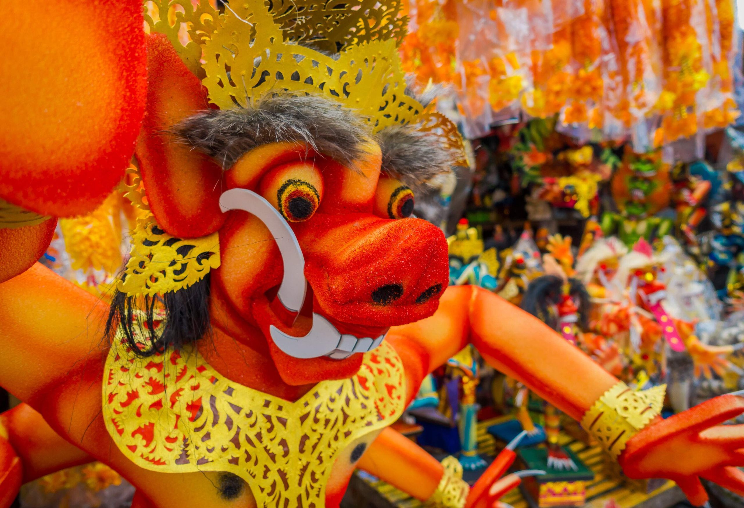 An orange statue of a mythological figure with gold decorations at a festival.