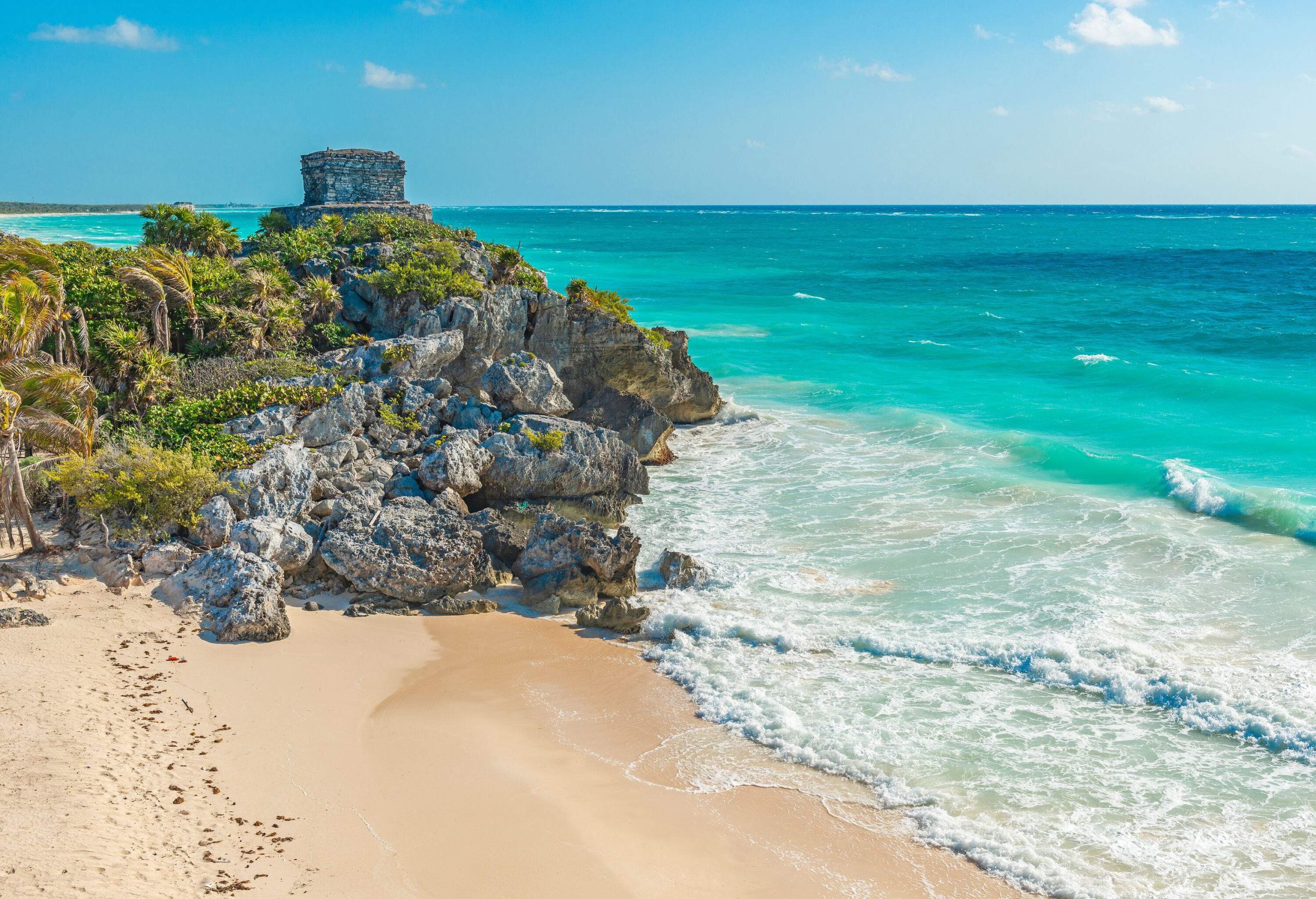 Ruins of a temple on a rocky outcrop overlooking the turquoise sea.