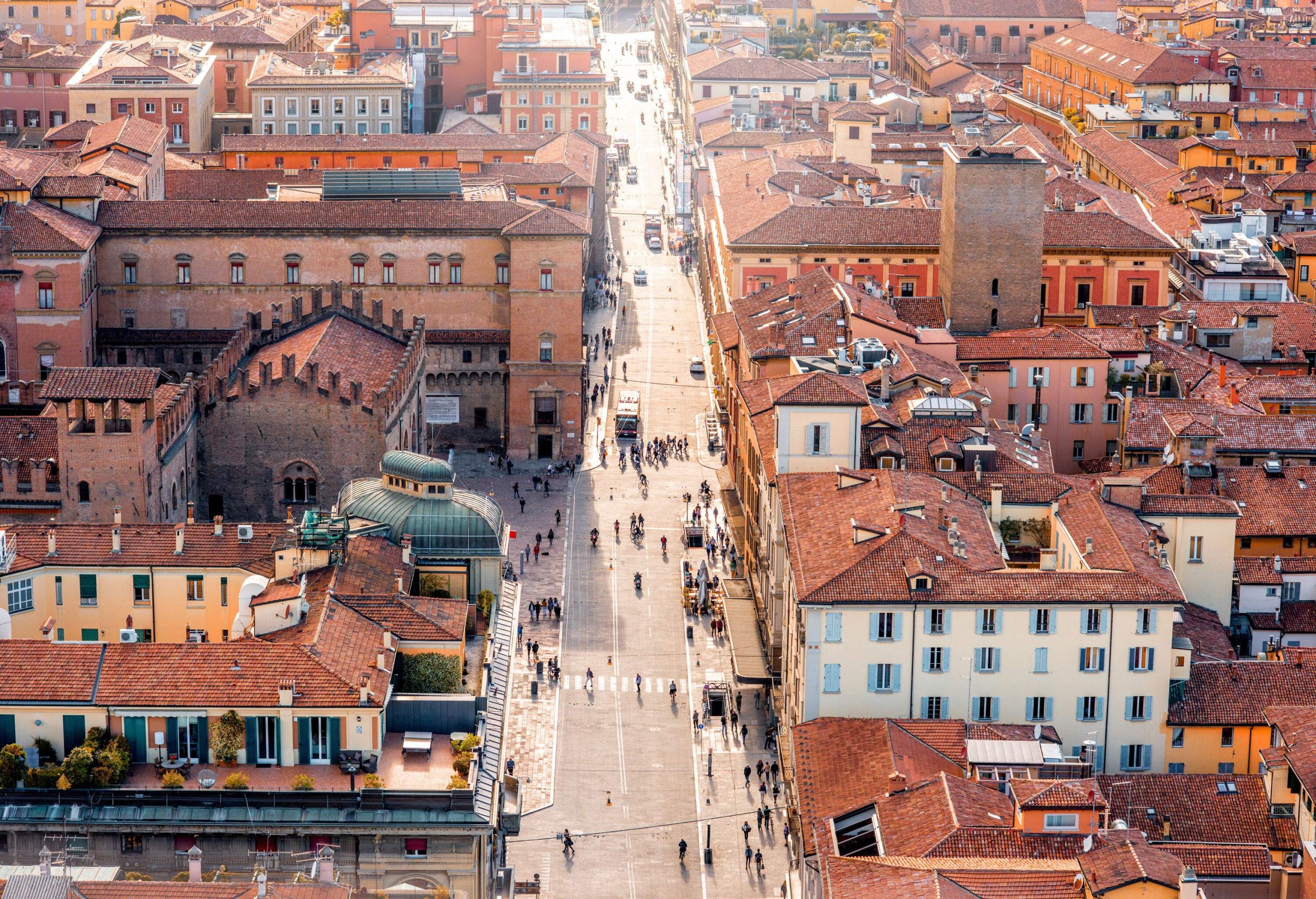 A crowded street across a cluster of buildings with red tile roofs.