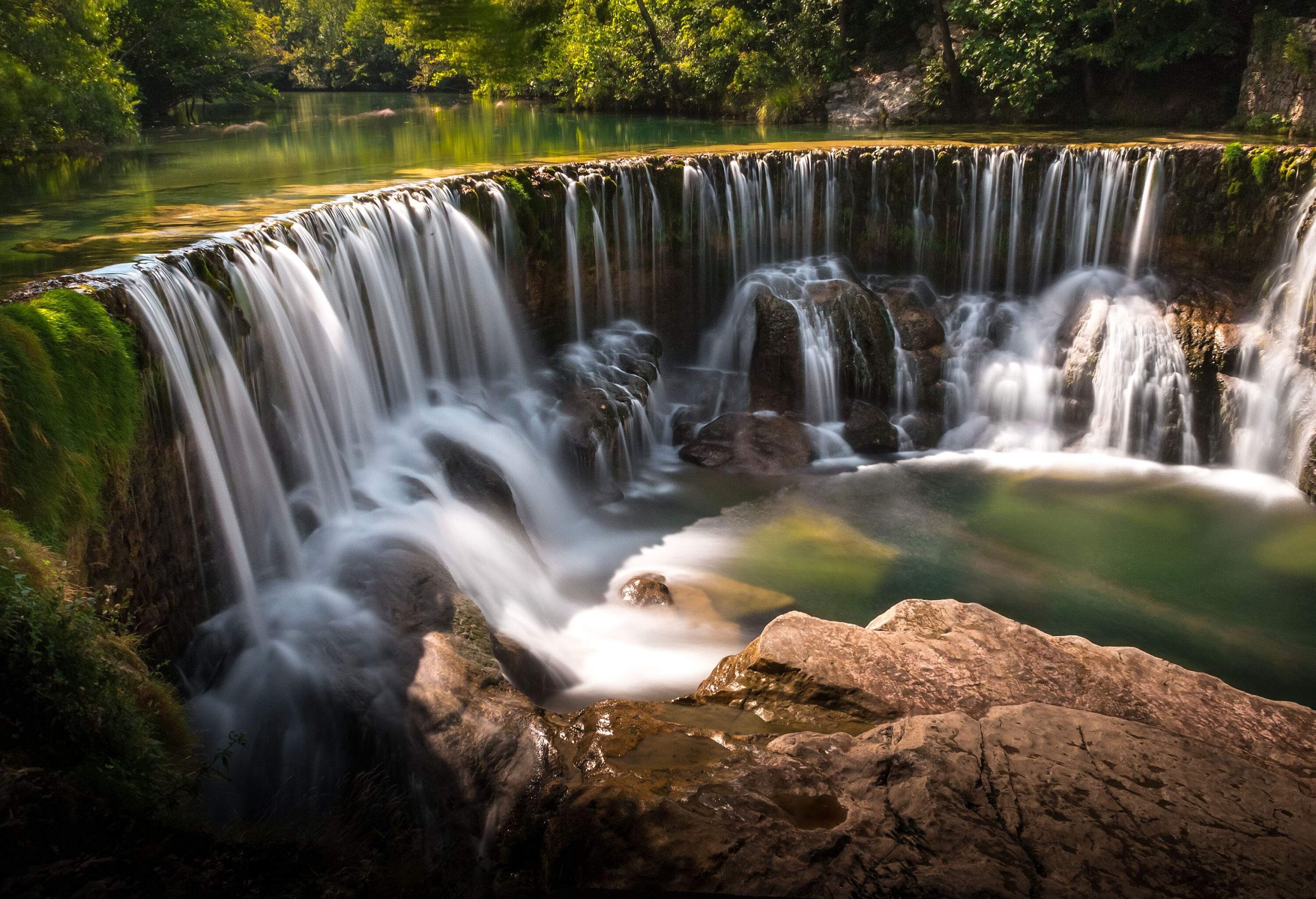 A waterfall in the jungle cascades into a rocky stream.