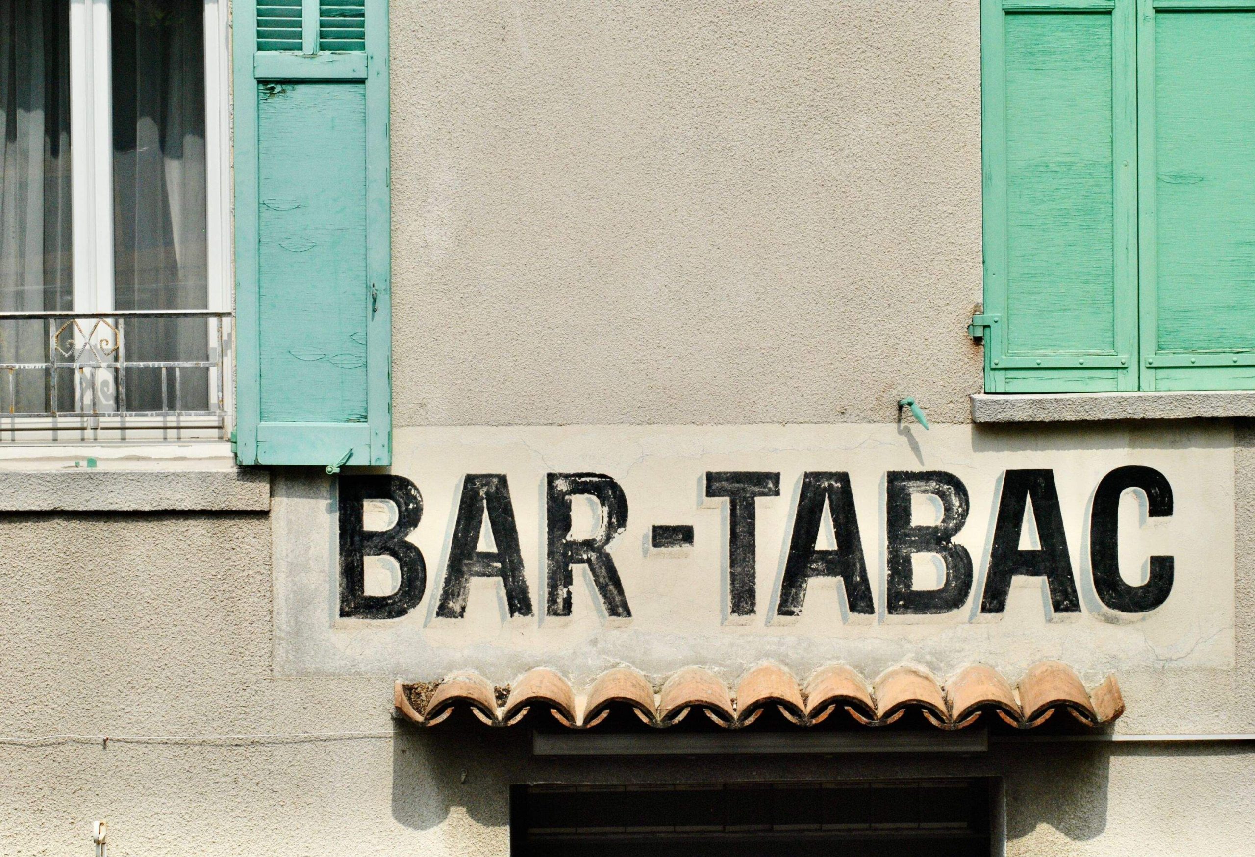 A close-up of the cafe sign with surrounding details of window, shutters and doorway.