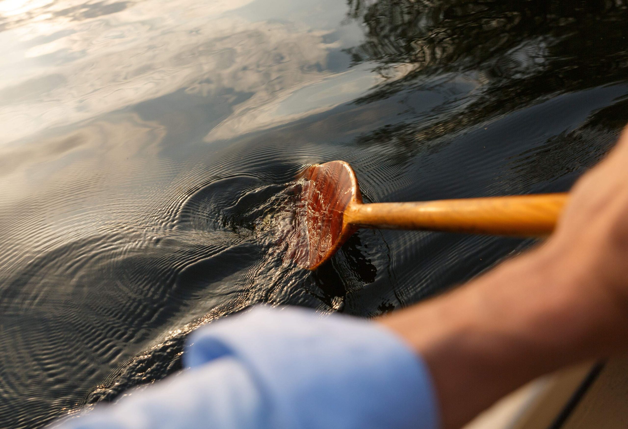 A person steering a boat with an oar through the lake.