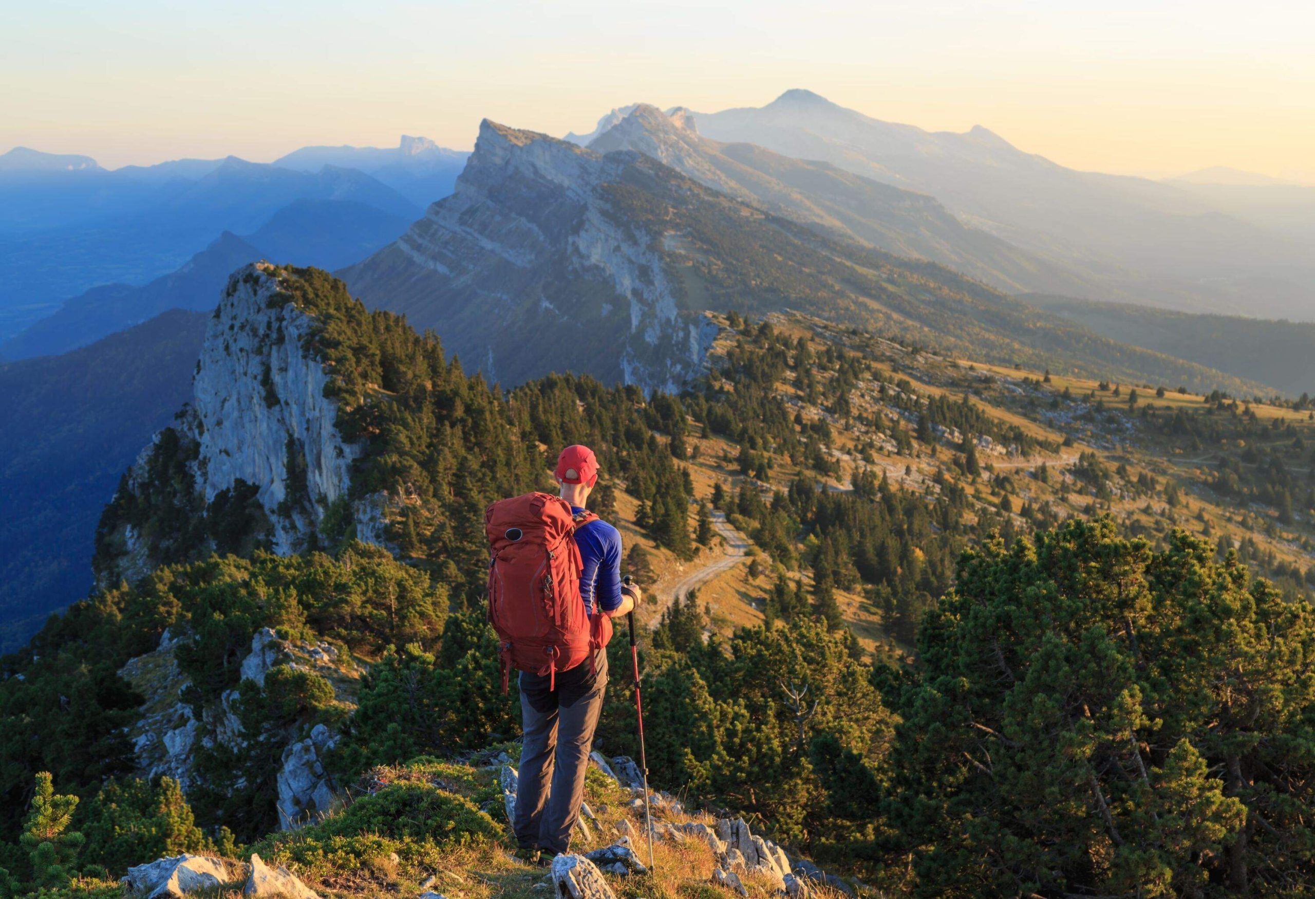 A hiker is looking over the mountains just before sunset. Les Vercors, France.