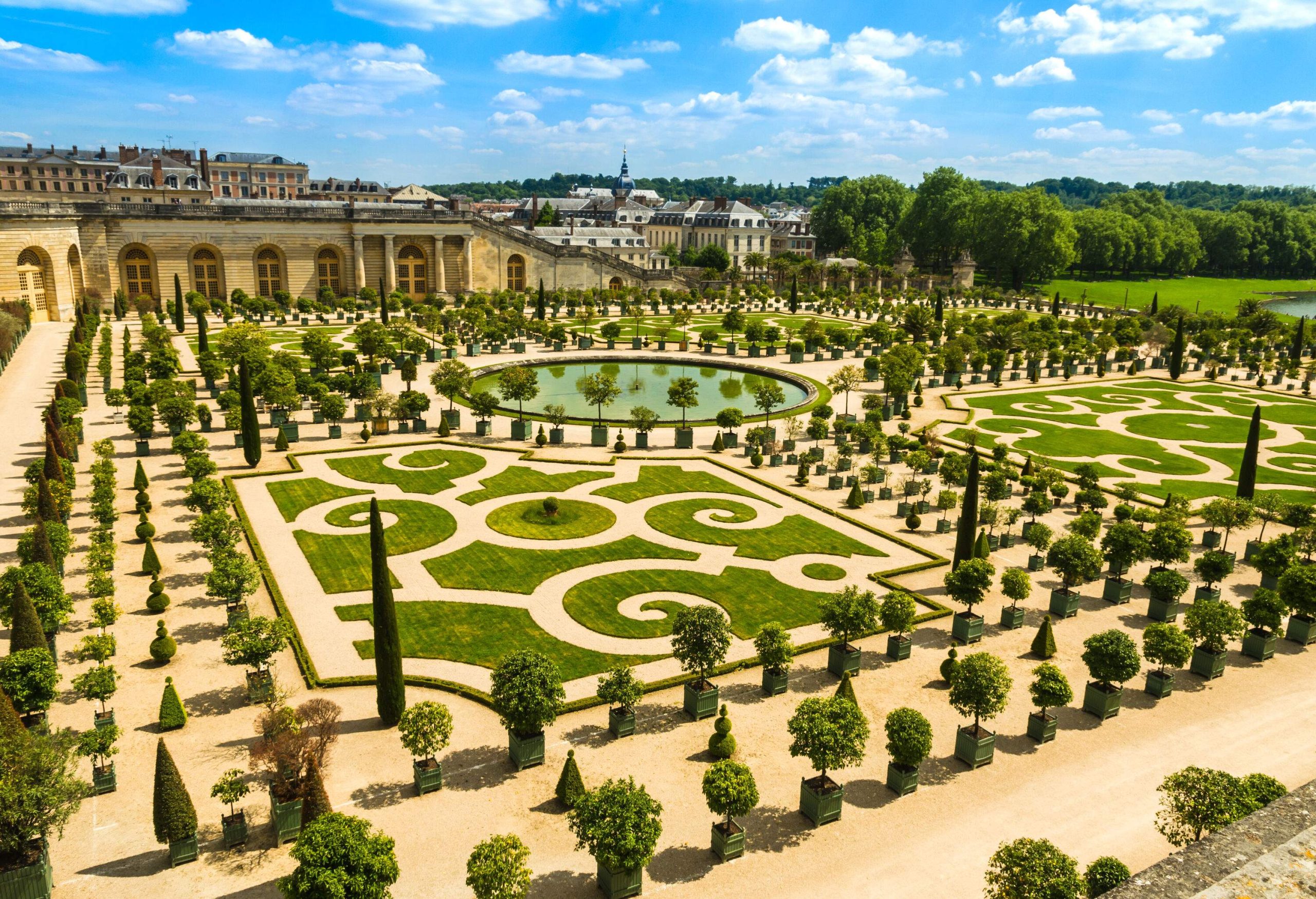 A large garden with manicured lawns and potted plants, as well as a circular pond in the centre.