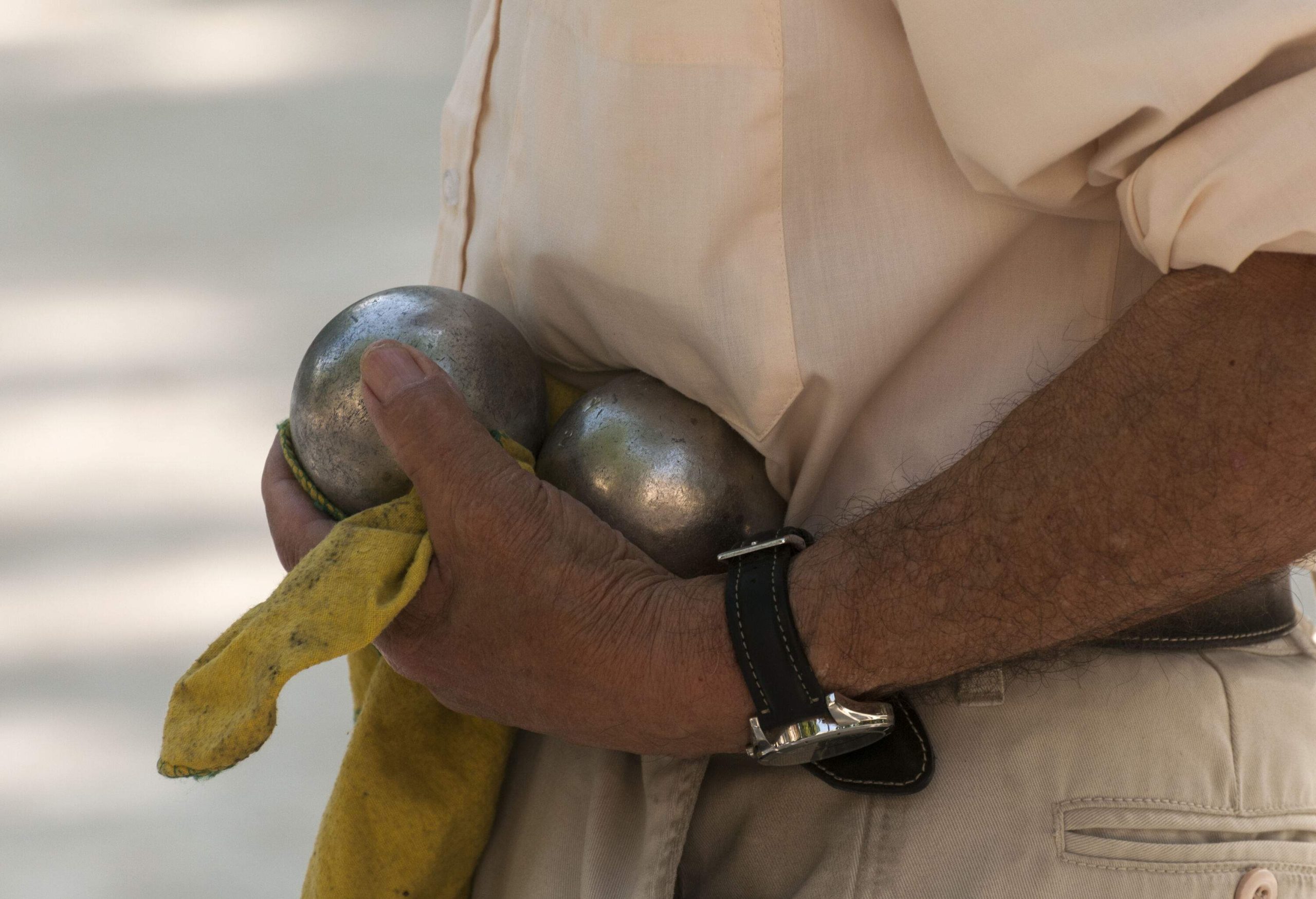 A person holding two boules while wearing a wristwatch.