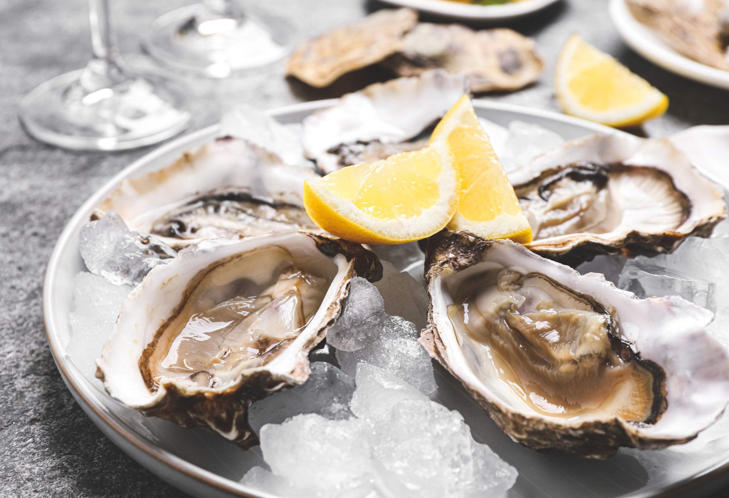 A platter of crushed ice with fresh oysters and lemon slices.