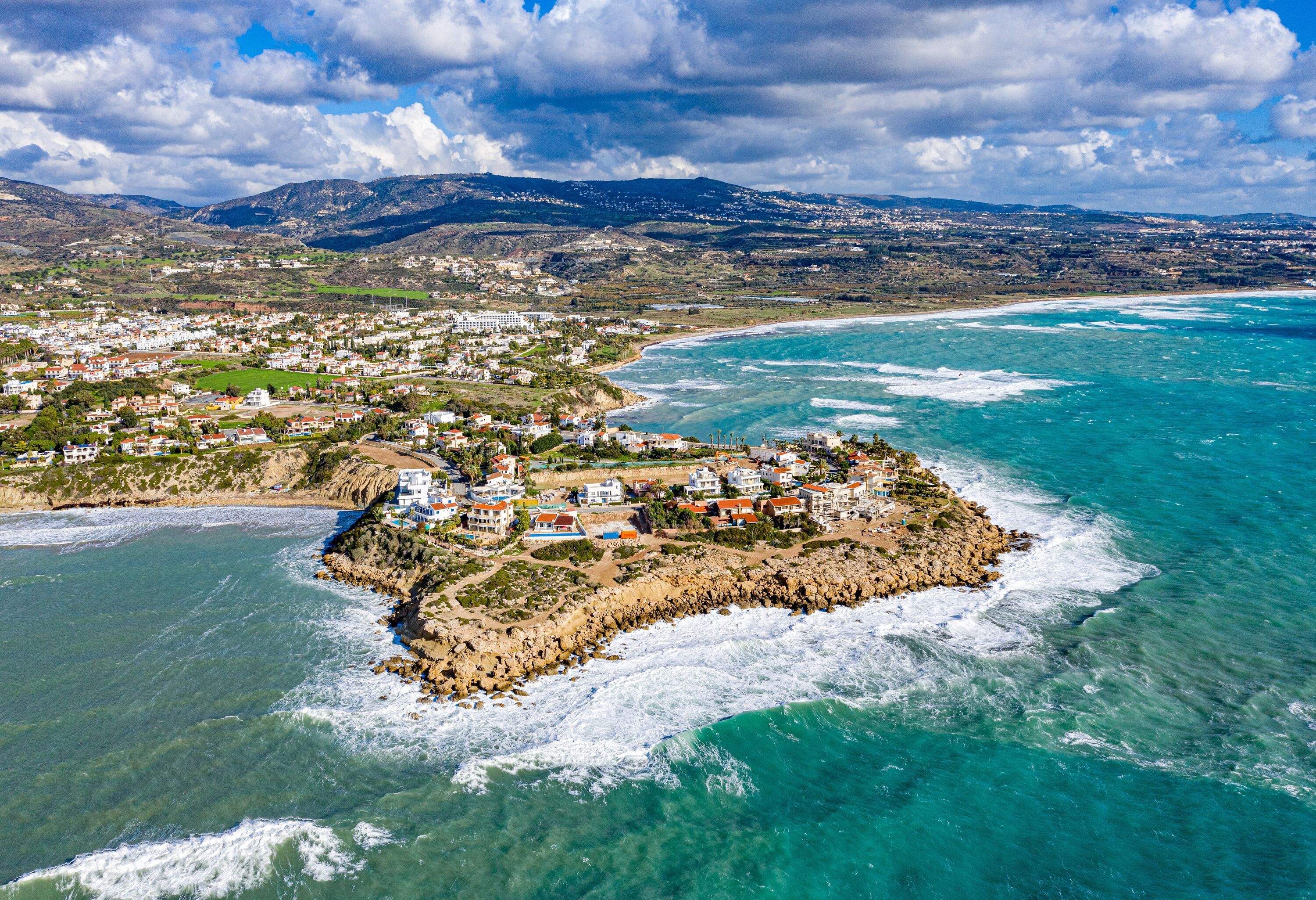 Waves pounding against the rocky edges of an island with sloping landscape in the background.