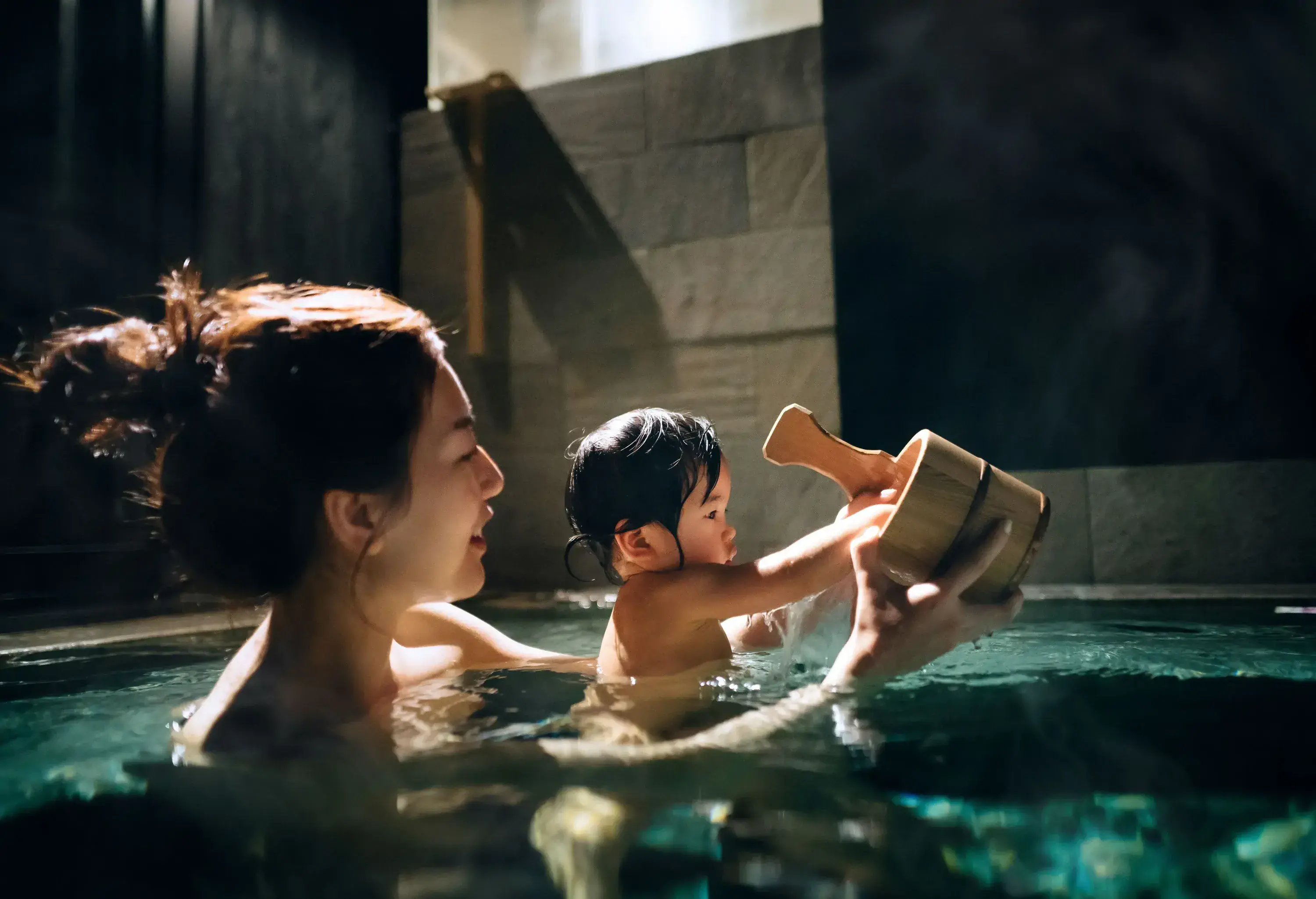 Young Asian mother and little daughter enjoying traditional Japanese natural onsen, hot spring bath together